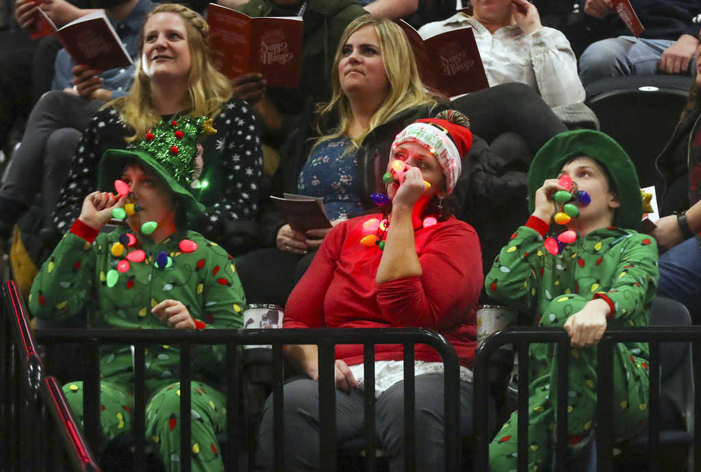 Brenda Banks and her children Abigail and Zacary Banks, right, hold red lights to their noses as they sing “Rudolph the Red-Nosed Reindeer” during the Larry H. Miller family’s 35th annual Christmas carol singalong at Vivint Smart Home Arena in Salt Lake City on Monday, Dec. 16, 2019. (Photo: Steve Griffin, KSL)