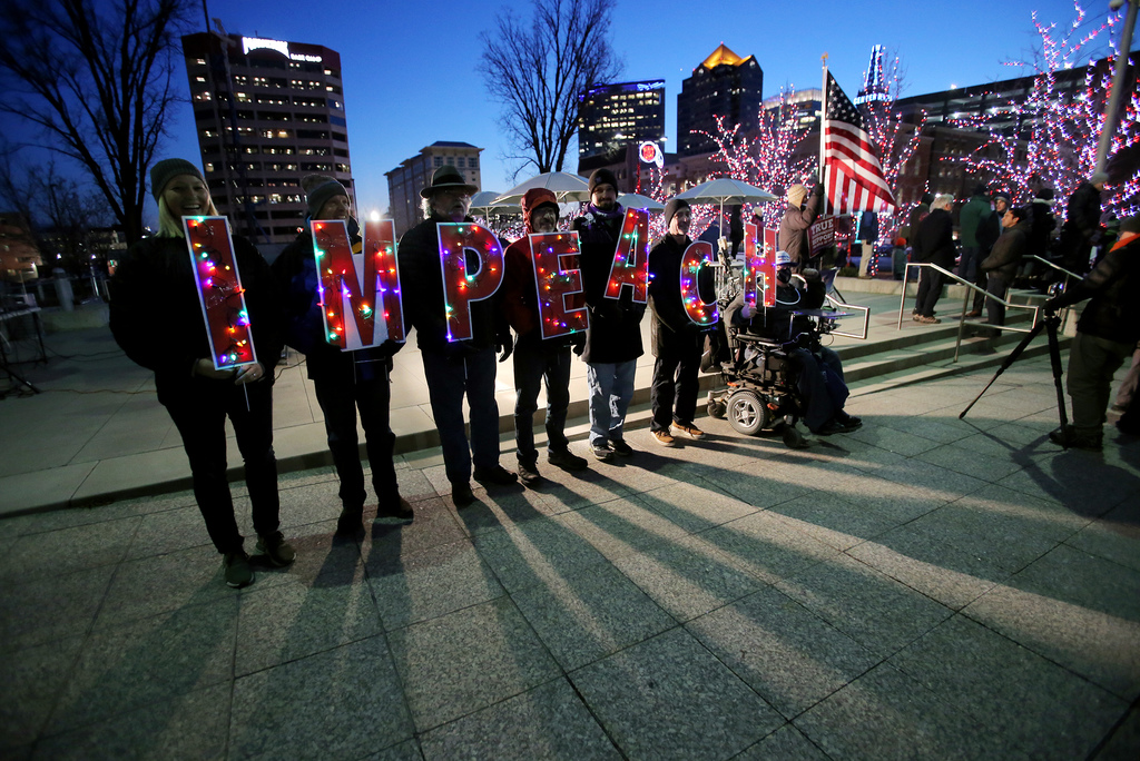 A group of protesters hold signs lit by Christmas lights that spell “Impeach” as several hundred people gather at the Wallace G. Bennett Federal Building in Salt Lake City to call for President Donald Trump’s impeachment on Tuesday, Dec. 17, 2019. (Photo: Scott G. Winterton, KSL)