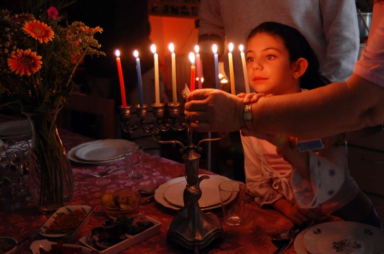 A child helps light the menorah during Hanukkah, which begins Sunday, Dec. 22, 2019. (Photo: Shutterstock)