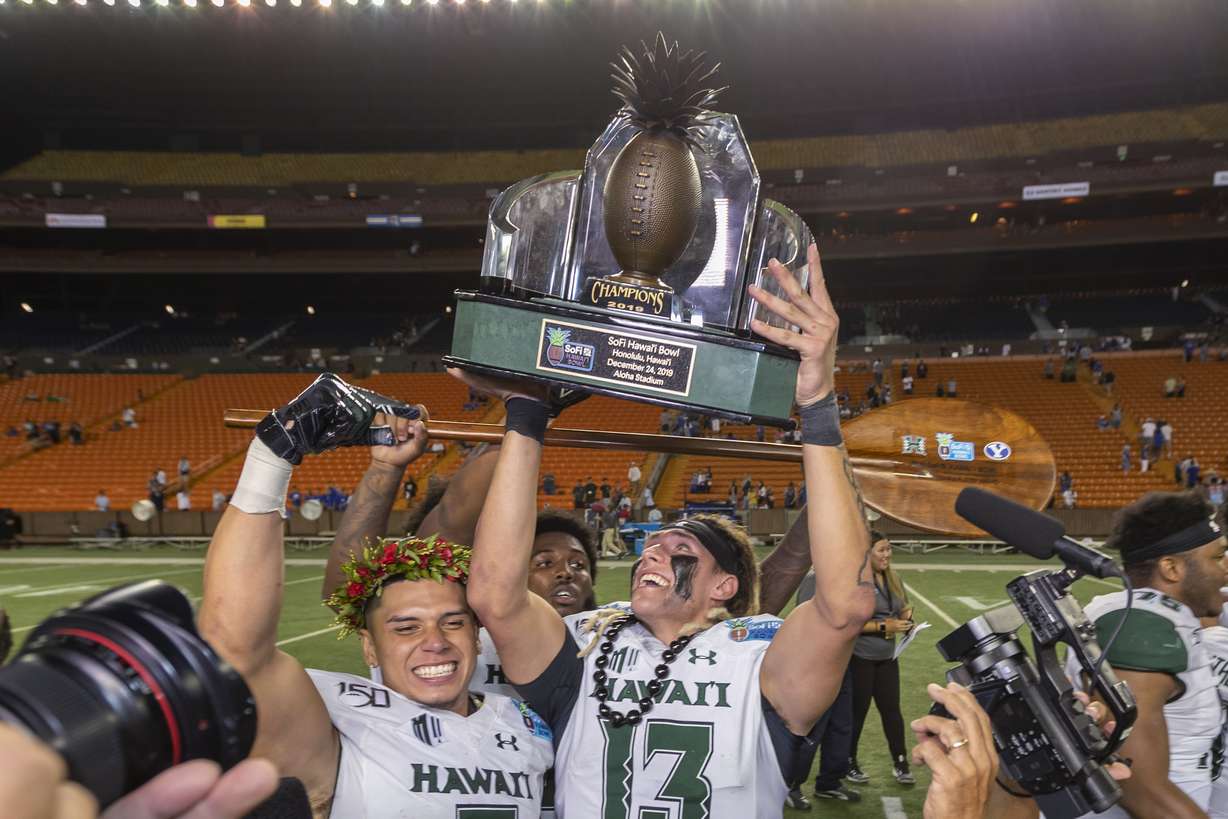 Hawaii quarterback Cole McDonald (13) holds up the Hawaii Bowl trophy, next to wide receiver Jason-Matthew Sharsh, left, after the team's 38-34 win over BYU in the NCAA college football game Tuesday, Dec. 24, 2019, in Honolulu. (Photo: Eugene Tanner, AP)