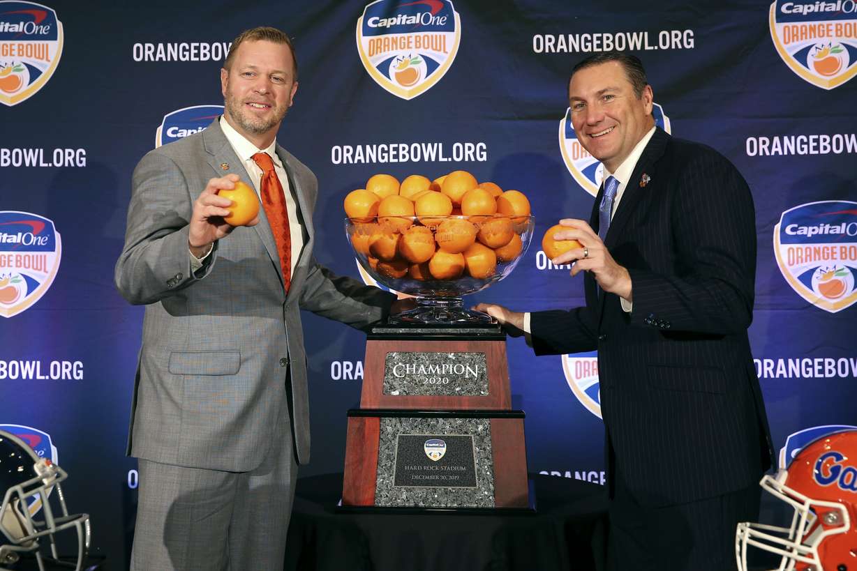 Virginia Cavaliers head coach Bronco Mendenhall, left, and Florida Gators head coach Dan Mullen, right, pose for a photograph during a news conference for the Orange Bowl NCAA college football game, Sunday, Dec. 29, 2019, in Fort Lauderdale, Fla. Florida plays Virginia in the Orange Bowl on Dec. 30.