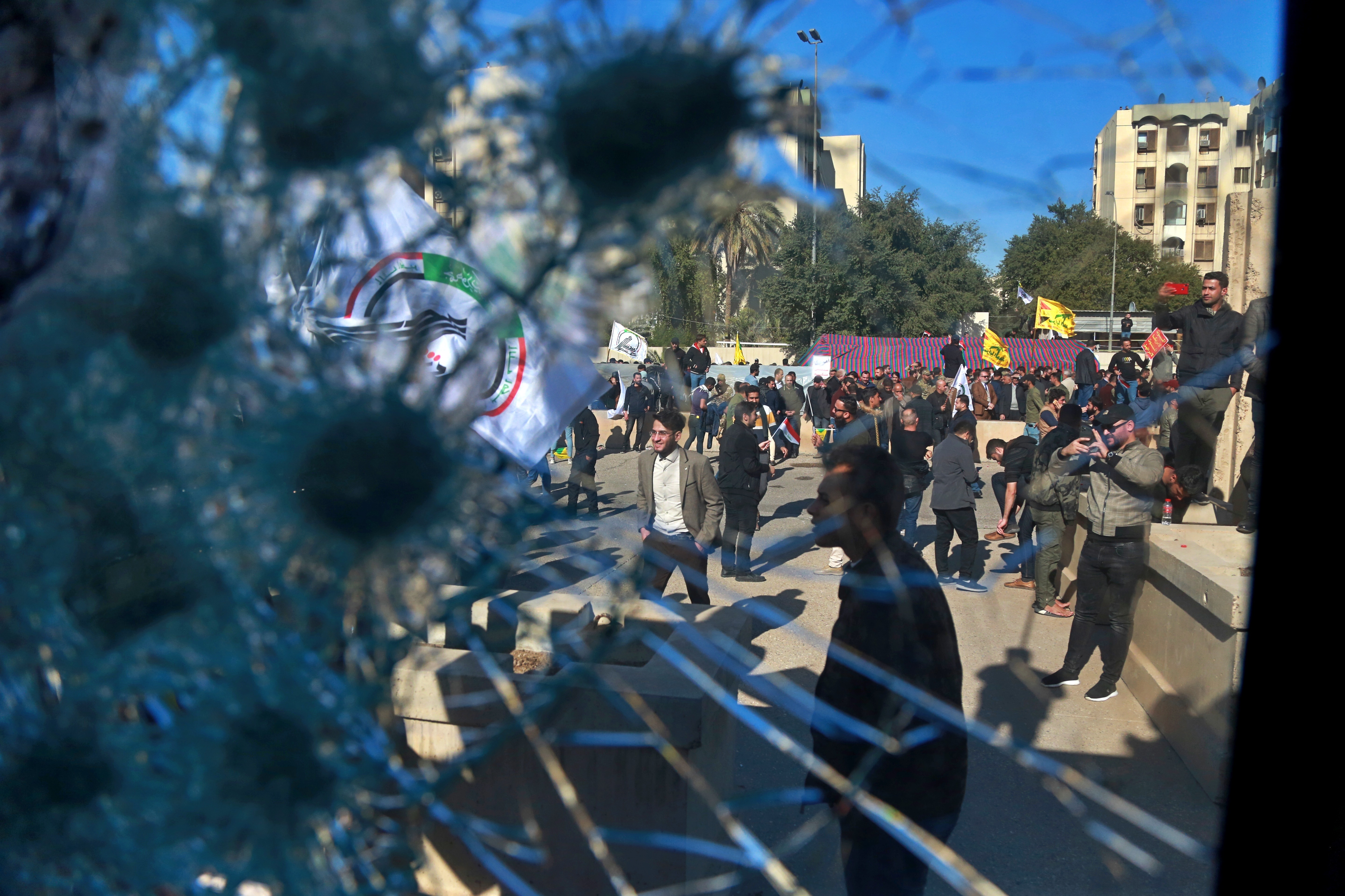 Shiite militia supporters are seen through a broken window of a checkpoint belonging to U.S. embassy, in front of the U.S. embassy, in Baghdad, Iraq, Tuesday, Dec. 31, 2019. Photo: Khalid Mohammed, AP Photo