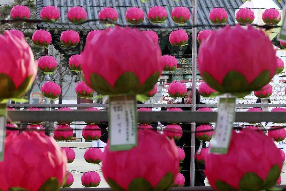 A woman attaches a paper note bearing her New Year wishes to a lantern at Jogyesa Buddhist temple in Seoul, South Korea, Tuesday, Dec. 31, 2019.(AP Photo/Ahn Young-joon)