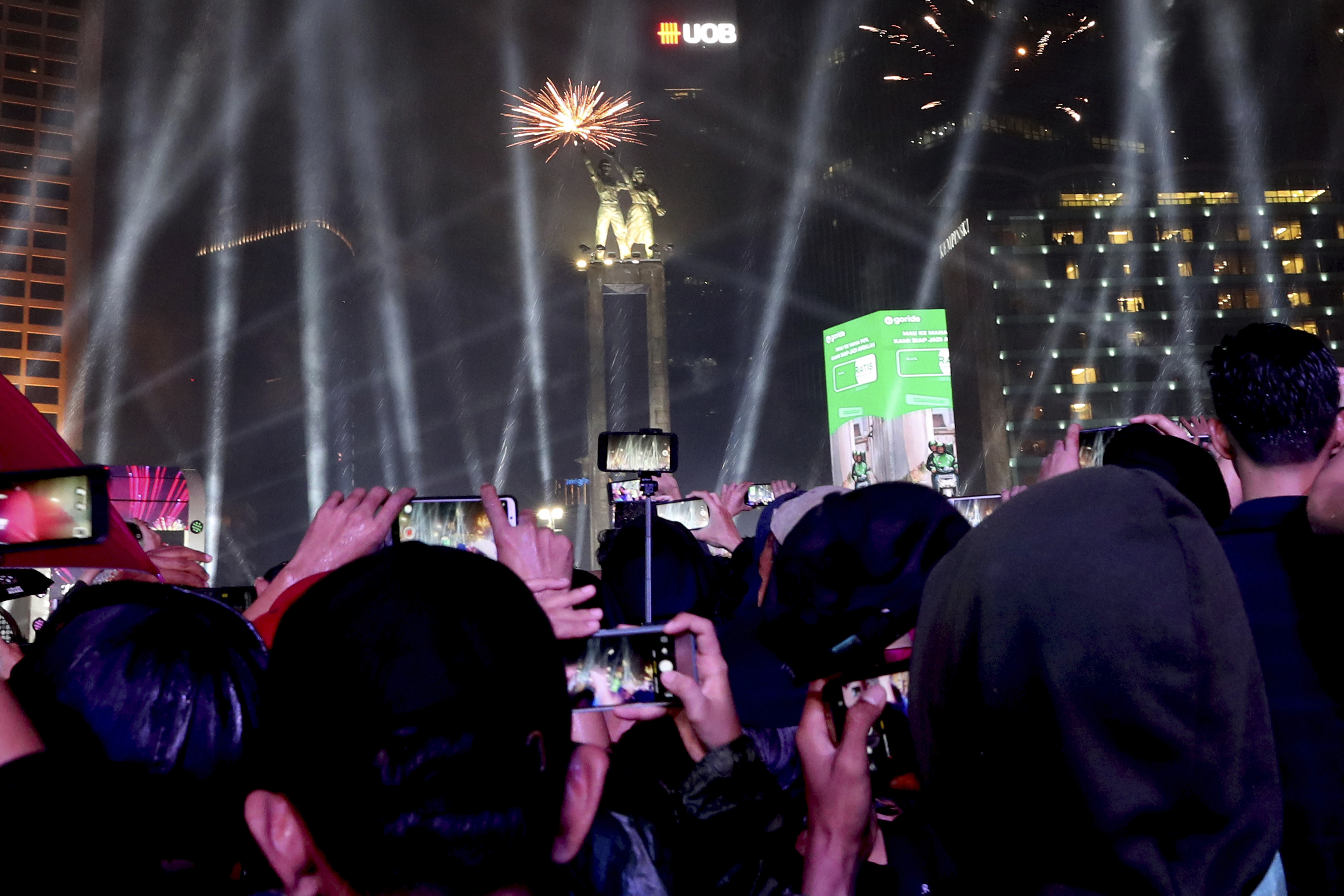 People watch fireworks light up the sky in the main business district on New Year's Eve in Jakarta, Indonesia, late Tuesday, Dec. 31, 2019. Tens of thousands of revelers in Indonesia's capital of Jakarta were soaked by torrential rains as they waited for New Year's Eve fireworks. (Tatan Syuflana, AP Photo)