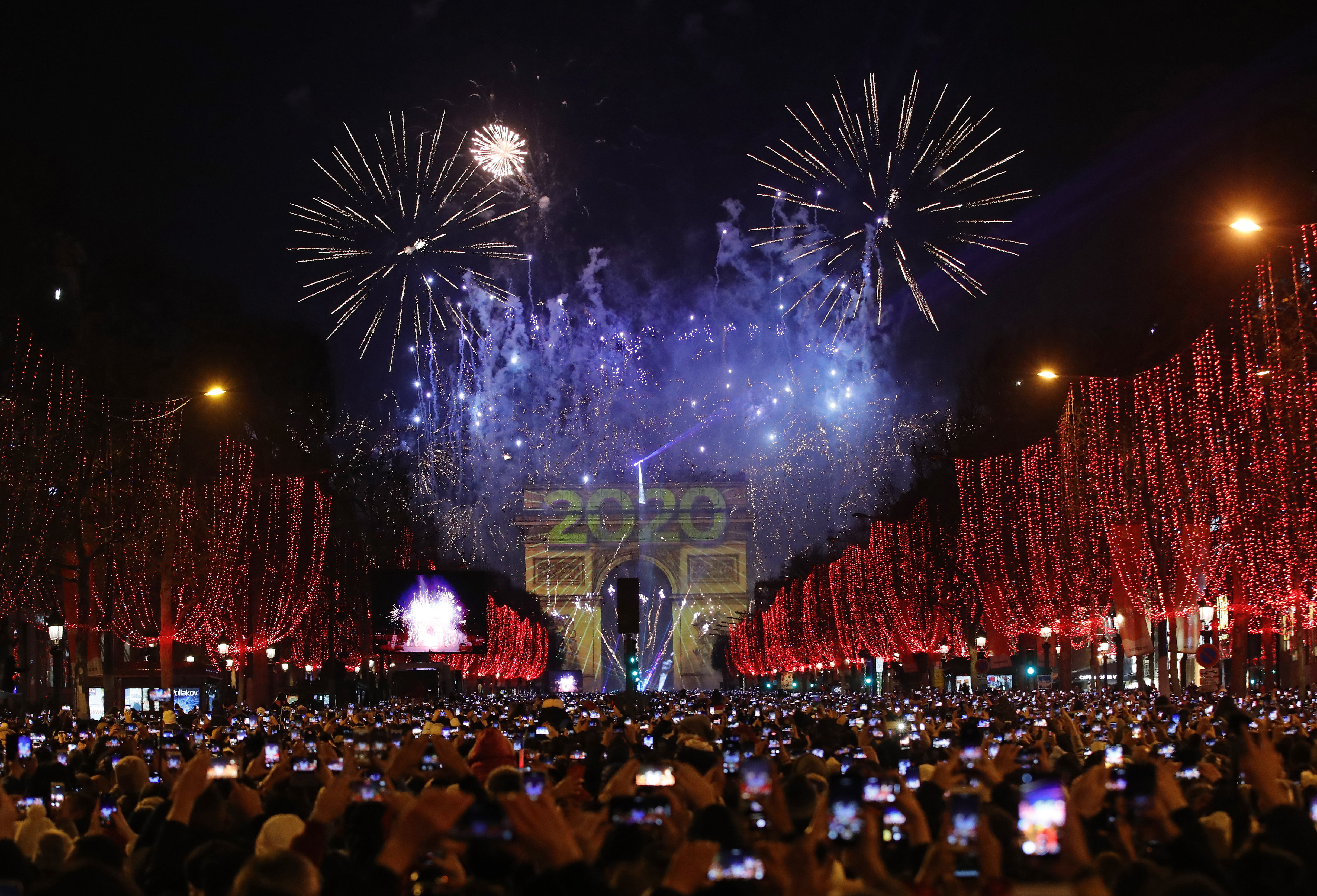 Revellers photograph fireworks over the Arc de Triomphe as they celebrate the New Year on the Champs Elysees, in Paris, France, Wednesday, Jan. 1, 2020. (Christophe Ena, AP Photo)