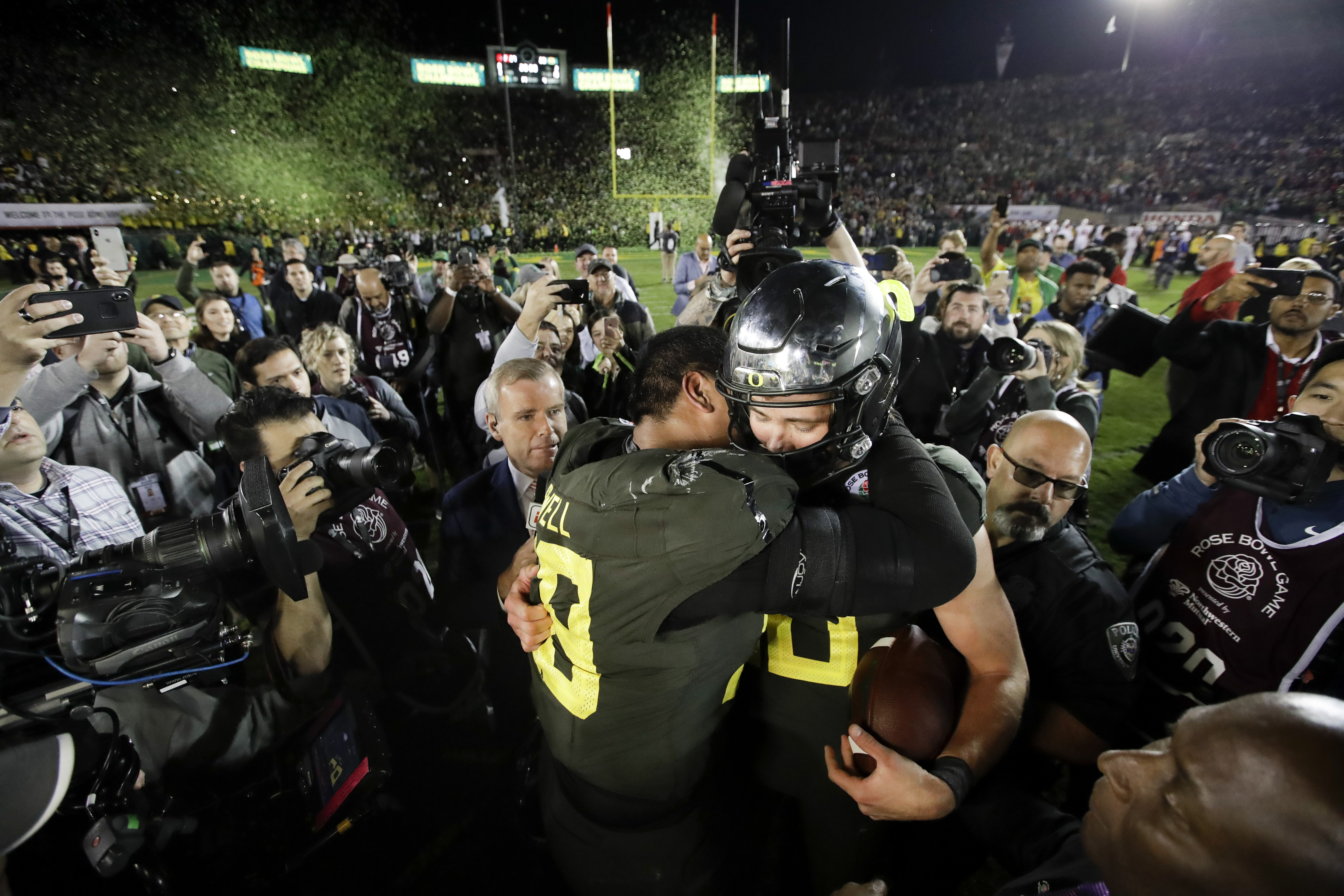 Oregon quarterback Justin Herbert, right, hugs offensive lineman Penei Sewell after their win against Wisconsin in the Rose Bowl NCAA college football game Wednesday, Jan. 1, 2020, in Pasadena, Calif. Sewell was drafted with the No. 7 overall pick Thursday by the Detroit Lions, joining Herbert — the quarterback for the LA Chargers — in the league next year.
