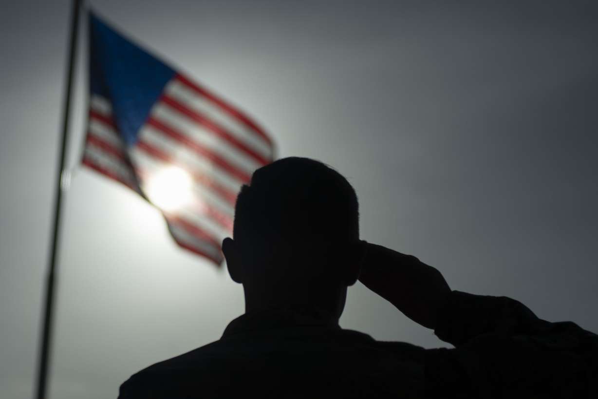 In this photo taken Aug. 26, 2019 and released by the U.S. Air Force, U.S. Air Force Staff Sgt. Devin Boyer, 435th Air Expeditionary Wing photojournalist, salutes the flag during a ceremony signifying the change from tactical to enduring operations at Camp Simba, Manda Bay, Kenya. (Staff Sgt. Lexie West, U.S. Air Force via AP)