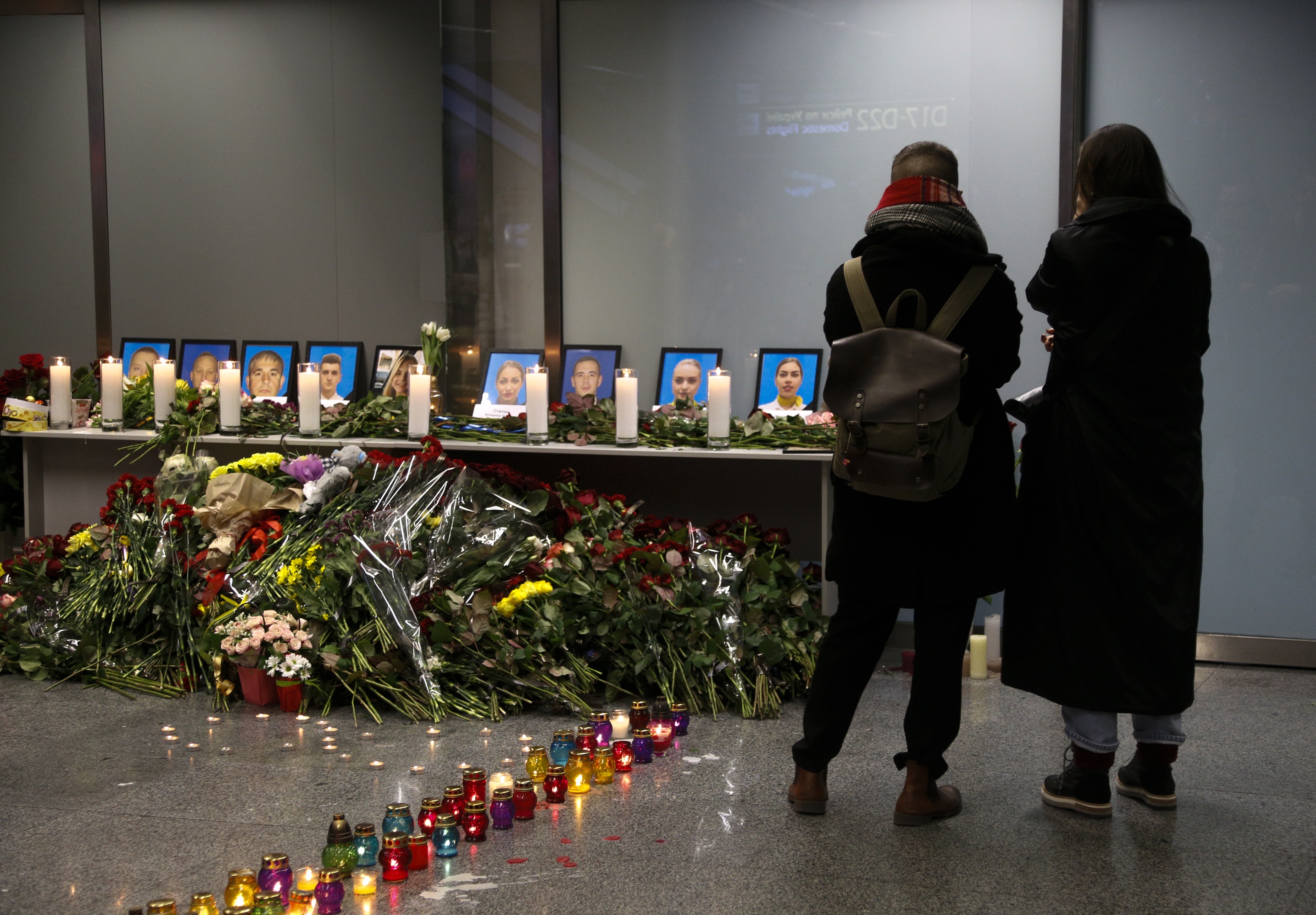 Two women mourn standing in front of a memorial for the flight crew of the Ukrainian 737-800 plane that crashed on the outskirts of Tehran, inside Borispil international airport outside Kyiv, Ukraine, late Wednesday, Jan. 8, 2020. (AP Photo/Efrem Lukatsky)