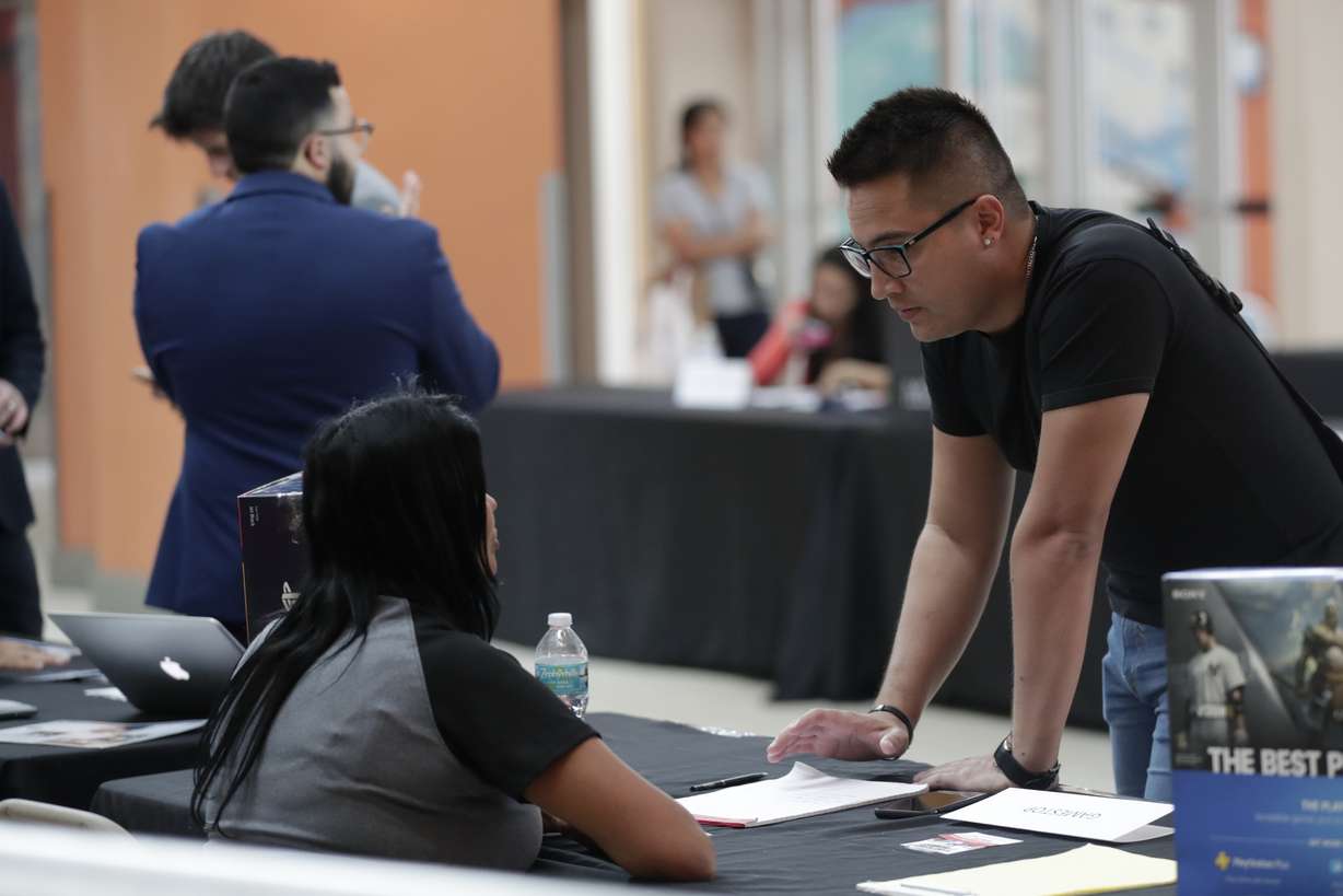 FILE - In this Oct. 1, 2019, file photo, Gabriel Picon, right, talks with a representative from GameStop during a job fair at Dolphin Mall in Miami. On Friday, Jan. 10, the U.S. government issues the December jobs report. (Lynne Sladky, AP Photo File)