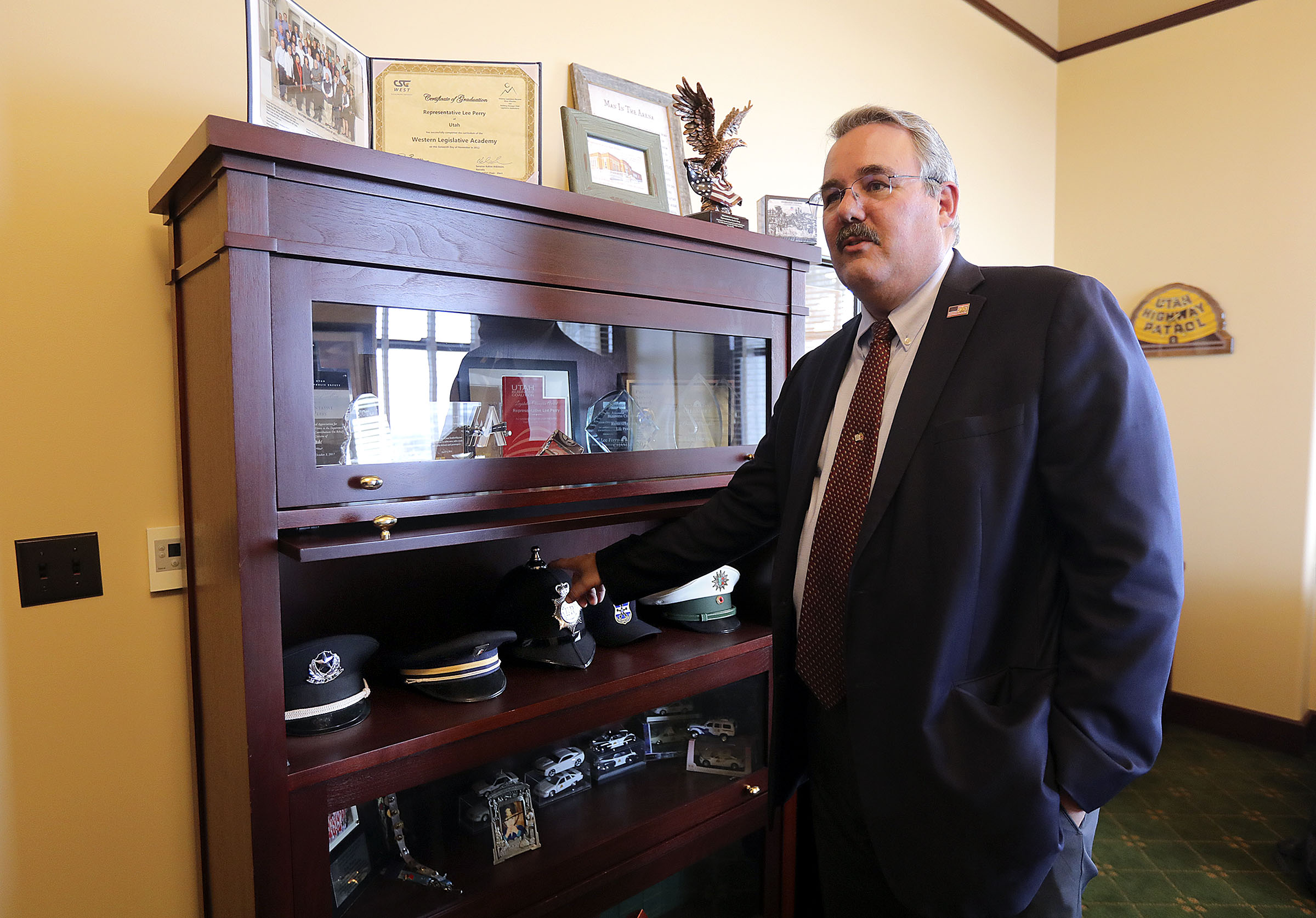 Rep. Lee Perry, R-Perry, shows police hats he collected throughout his 31-year career with the Utah Highway Patrol at his office in the Capitol in Salt Lake City on Wednesday, Jan. 8, 2020. (Kristin Murphy, KSL)