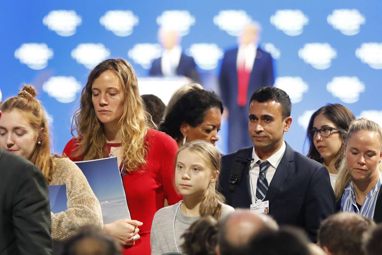 Swedish environmental activist Greta Thunberg, center, leaves as U.S. President Donald Trump, rear right, and Executive Chairman Klaus Schwab, rear left, are seen at the World Economic Forum in Davos, Switzerland, Tuesday, Jan. 21, 2020. The 50th annual meeting of the forum will take place in Davos from Jan. 21 until Jan. 24, 2020. (AP Photo/Markus Schreiber)
