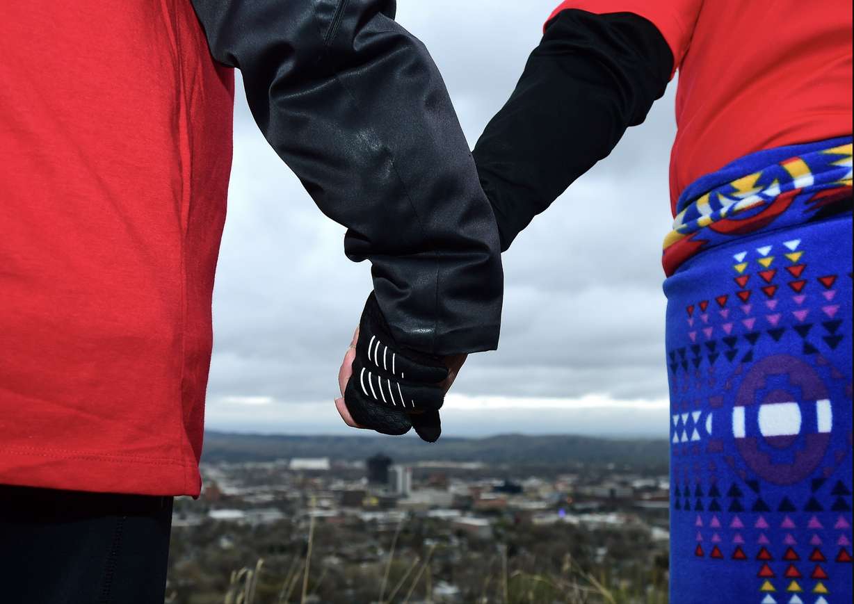 In this May 5, 2019, photo, hundreds hold hands as they form a line of the edge of the Billings Rimrocks for Line the Rims in Red event to honor missing and murdered indigenous people, in Billings, Mont. The event was organized by MSU Billings and community partners. Participants brought posters of men, women and children who are missing, and changed the name of the local movement to Missing and Murdered Indigenous People. (Larry Mayer/The Billings Gazette via AP)