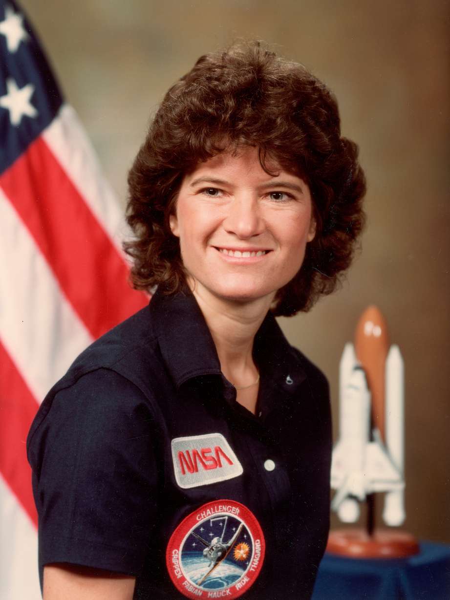 American astronaut Sally Ride poses in a NASA shirt with a logo of the Challenger Space Shuttle STS-7 mission, in front of an American flag and a model of the shuttle, Johnson Space Center, Houston, Texas, June 1984. On June 18, 1984, Ride became the third woman (and first American woman) in space. Photo: NASA/The LIFE Picture Collection via Getty Images