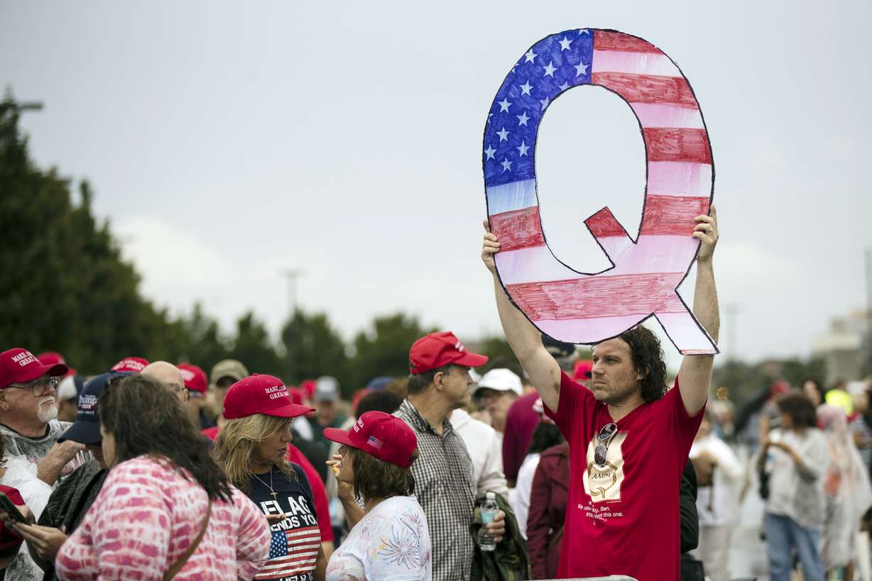 In this Aug. 2, 2018, file photo, David Reinert holding a Q sign waits in line with others to enter a campaign rally with President Donald Trump in Wilkes-Barre, Pa. A far-right conspiracy theory forged in a dark corner of the internet is creeping into the mainstream political arena. It's called QAnon, and it centers on the baseless belief that President Donald Trump is waging a secret campaign against enemies in the “deep state.”