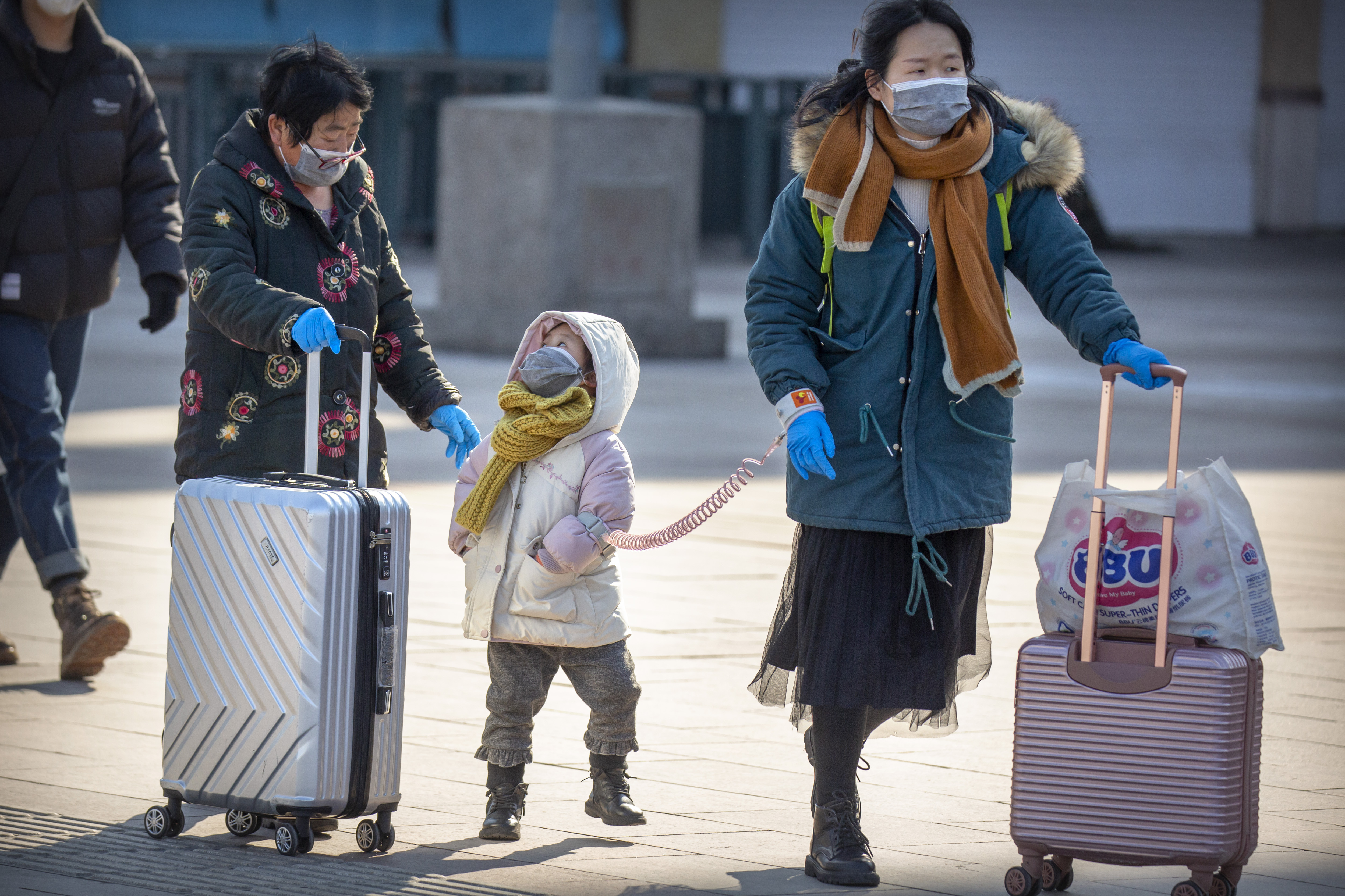 Travelers wear face masks as they walk outside the Beijing Railway Station in Beijing, Saturday, Feb. 15, 2020. People returning to Beijing will now have to isolate themselves either at home or in a concentrated area for medical observation, said a notice from the Chinese capital's prevention and control work group published by state media late Friday. (Mark Schiefelbein, AP Photo)