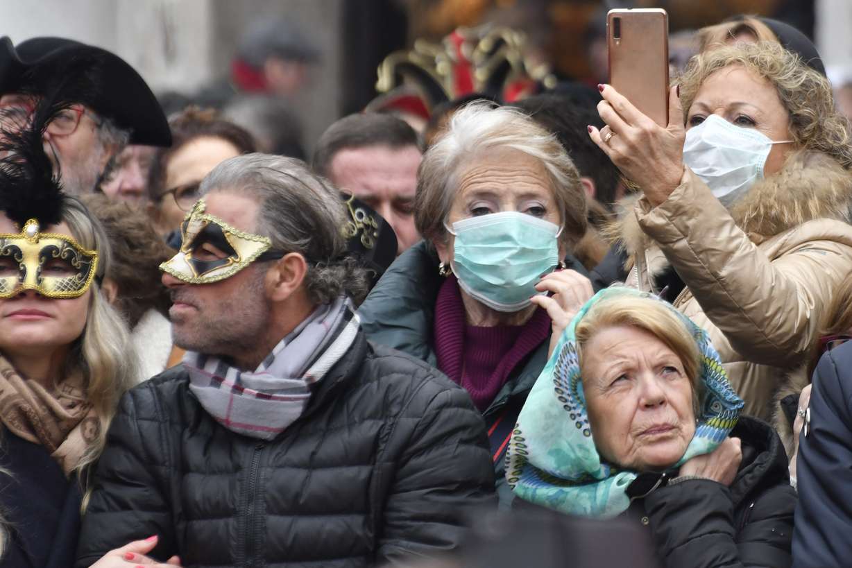 Masks mix with sanitary masks in the last day of carnival, as authorities decided to cut it two days shorter, in Venice, Sunday, Feb. 23, 2020. Italian authorities have announced they are shutting down Venice's famed carnival events in a bid to stop the spread of the novel virus, as numbers of infected persons in the country have soared to at least 133, the largest amount of cases outside Asia. (Luigi Costantini, AP Photo)