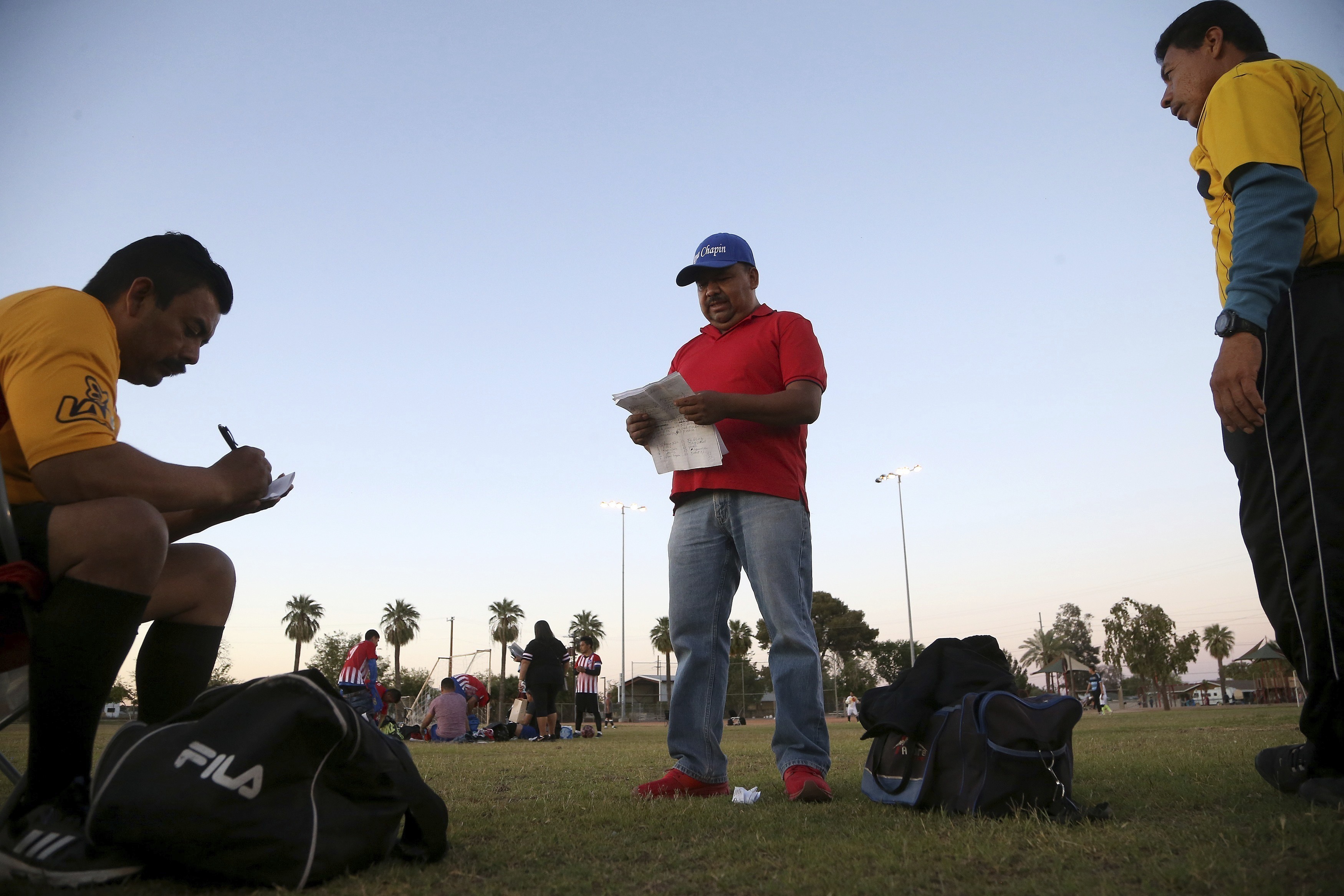 FILE - In this April 17, 2019, file photo Antonio Velasquez, center, a pastor and director of the Maya Chapin soccer league, gives referees their game assignments in Phoenix. Velasquez says before the Trump administration announced a crackdown on immigrants using government social services, people lined up before sunrise outside a state office in his neighborhood to sign up for food stamps and Medicaid. (Ross D. Franklin, AP Photo, File)