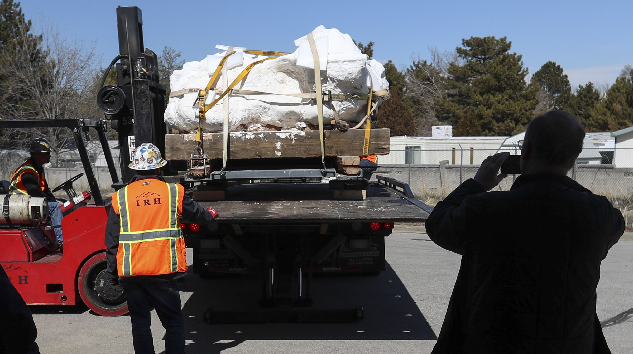 Bill Keach, director of the Utah Geological Survey, right, photographs an 18,000-pound sandstone block full of dinosaur bones as it is moved into the Utah Department of Natural Resources’ Utah Core Research Center in Salt Lake City on Wednesday, Feb. 26, 2020. Paleontologists say the block contains the best known preserved and most complete collection of Utahraptor skeletons ever found. It’s believed the block contains the remains of at least six, and possibly more, Utahraptors, including one adult, four juveniles and one baby. Moving the block will allow Utah Geological Survey paleontologists, staff and university students to work more closely and frequently with the block to extract and prepare bones and fossils. (Steve Griffin, KSL)