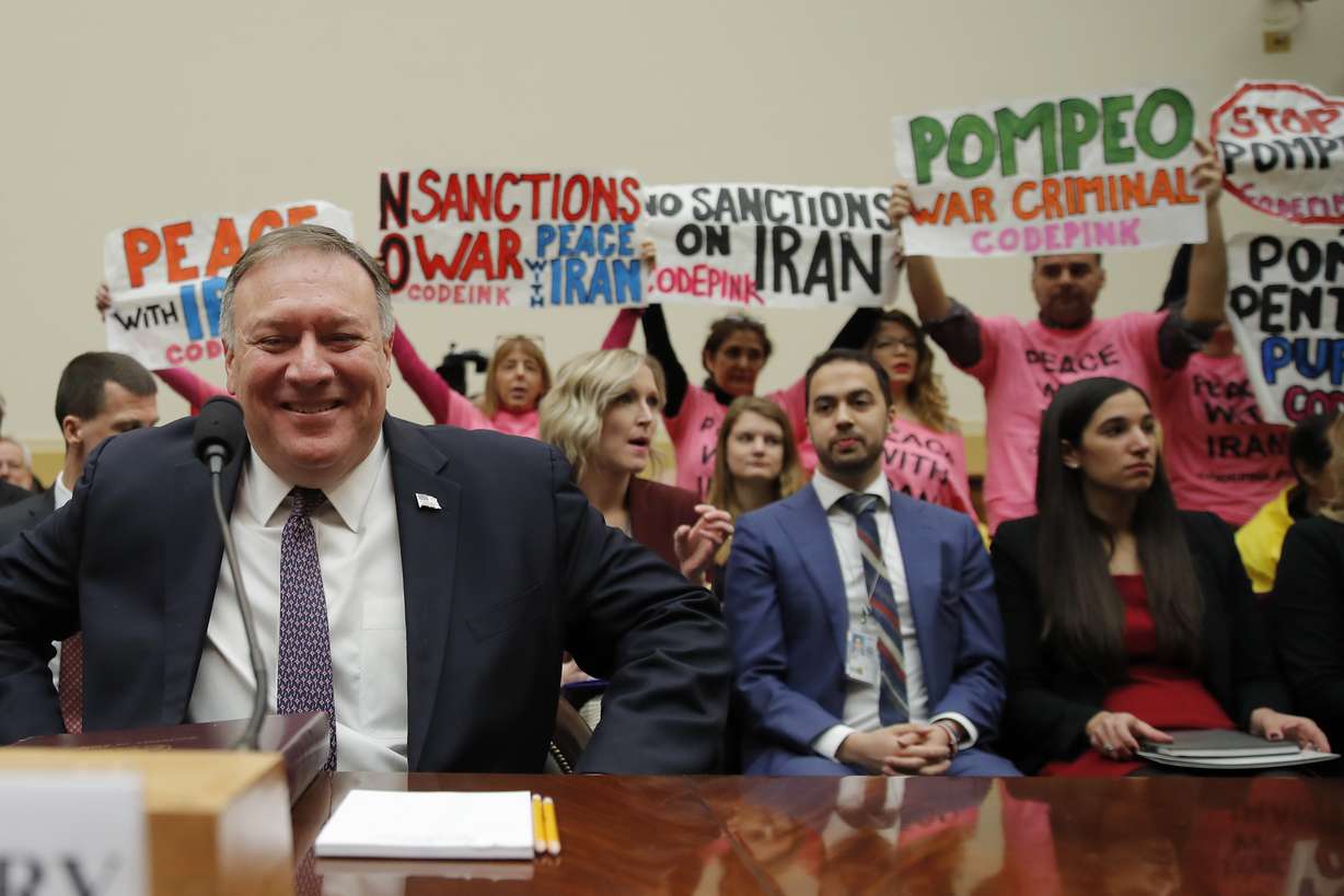 Protesters hold up signs as Secretary of State Mike Pompeo arrives to testify at a House Foreign Affairs Committee hearing on Capitol Hill in Washington, Friday, Feb. 28, 2020, about the Trump administration's policies on Iran, Iraq and the use of force. (Carolyn Kaster, AP Photo)
