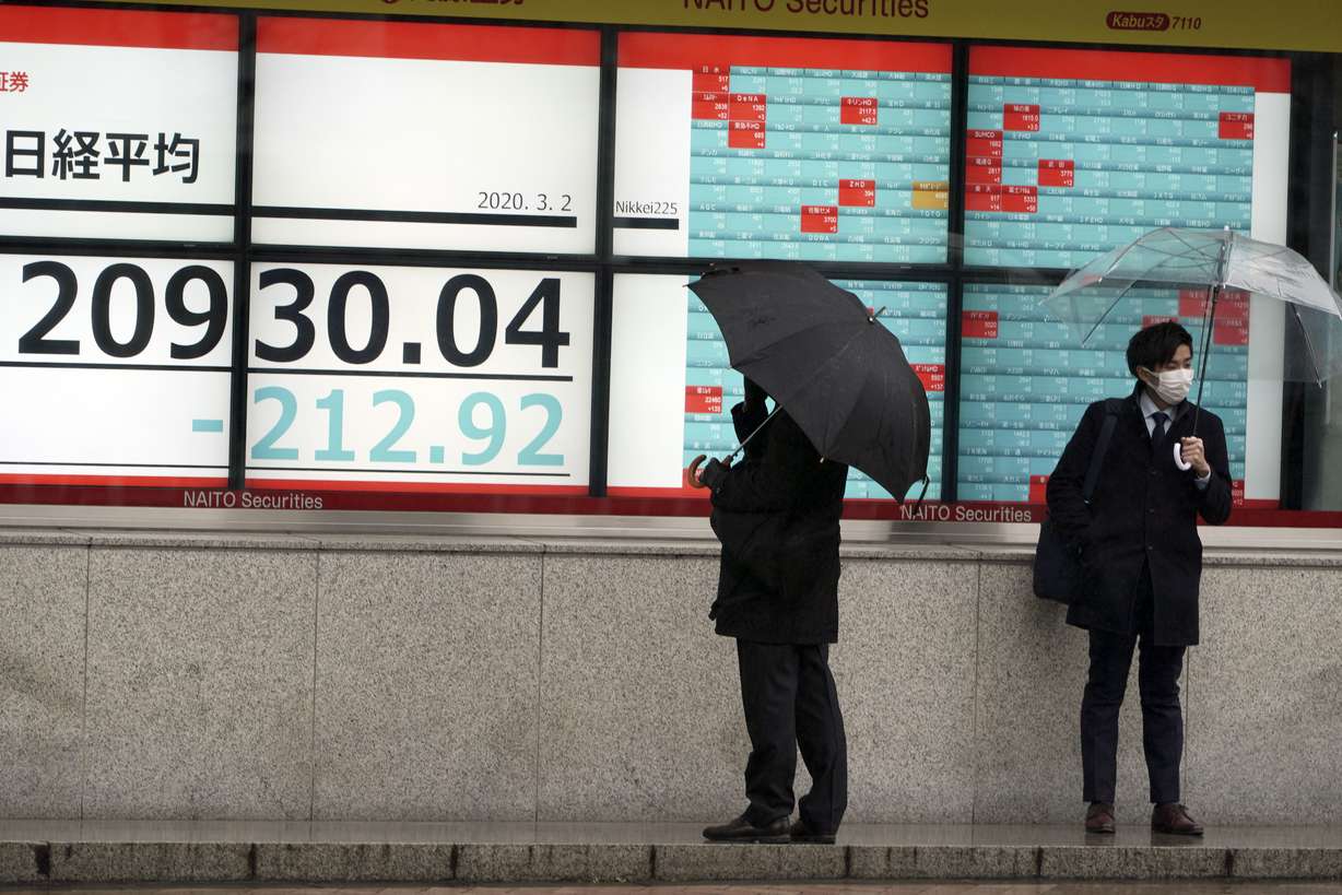 People stand in front of an electronic stock board showing Japan's Nikkei 225 index at a securities firm in Tokyo Monday, March 2, 2020. Photo: AP Photo
