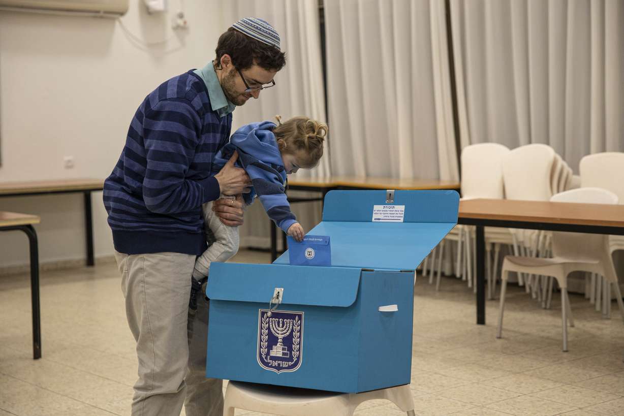 An Israeli settler casts a vote with his son during elections in the settlement of Alon Shvut, West Bank, Monday, March 2, 2020. (Tsafrir Abayov, AP Photo)