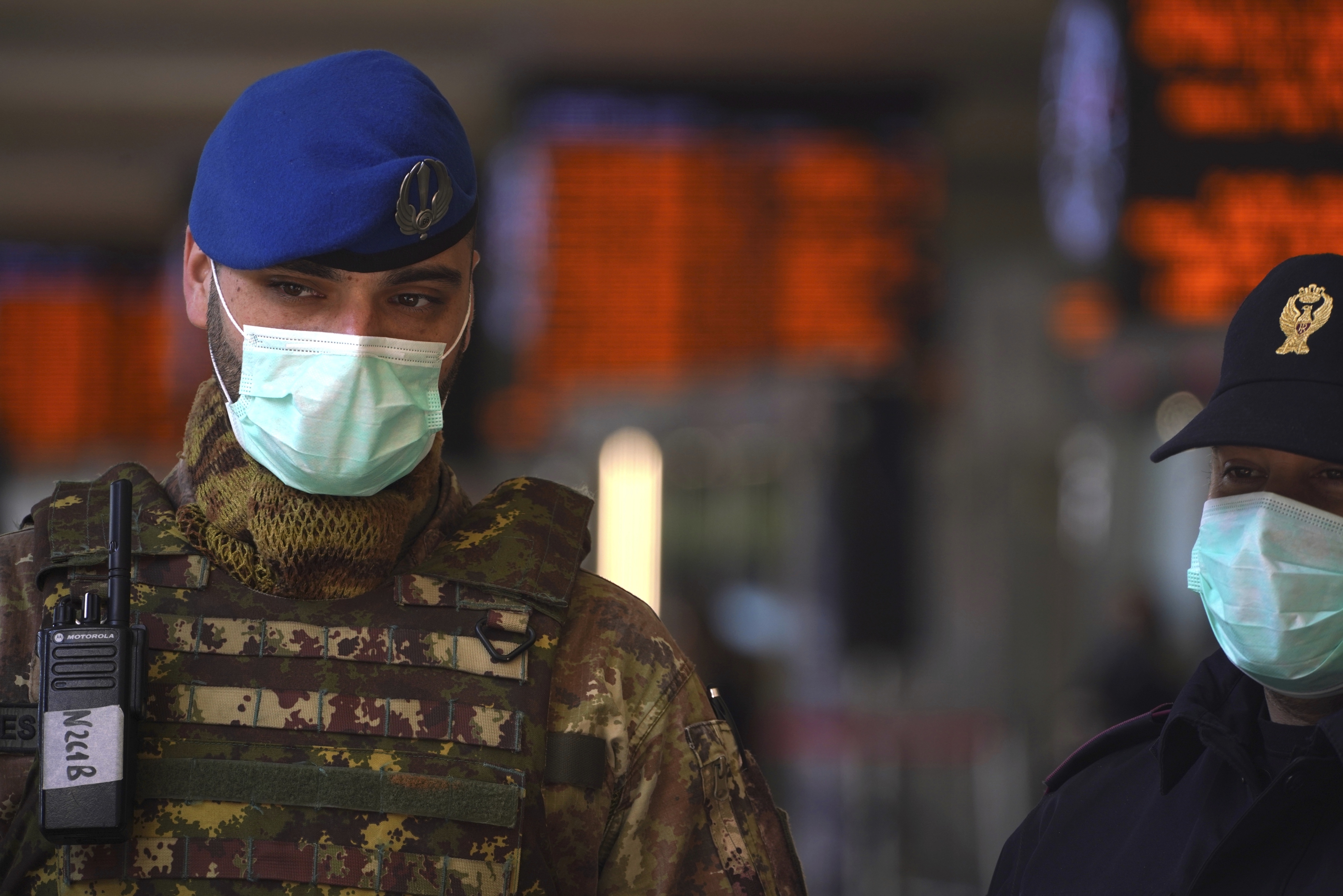 An Italian soldier and border police officer wear masks as they monitor the travelers' situation inside Rome's Termini train station, Tuesday, March 10, 2020. (AP Photo/Andrew Medichini)