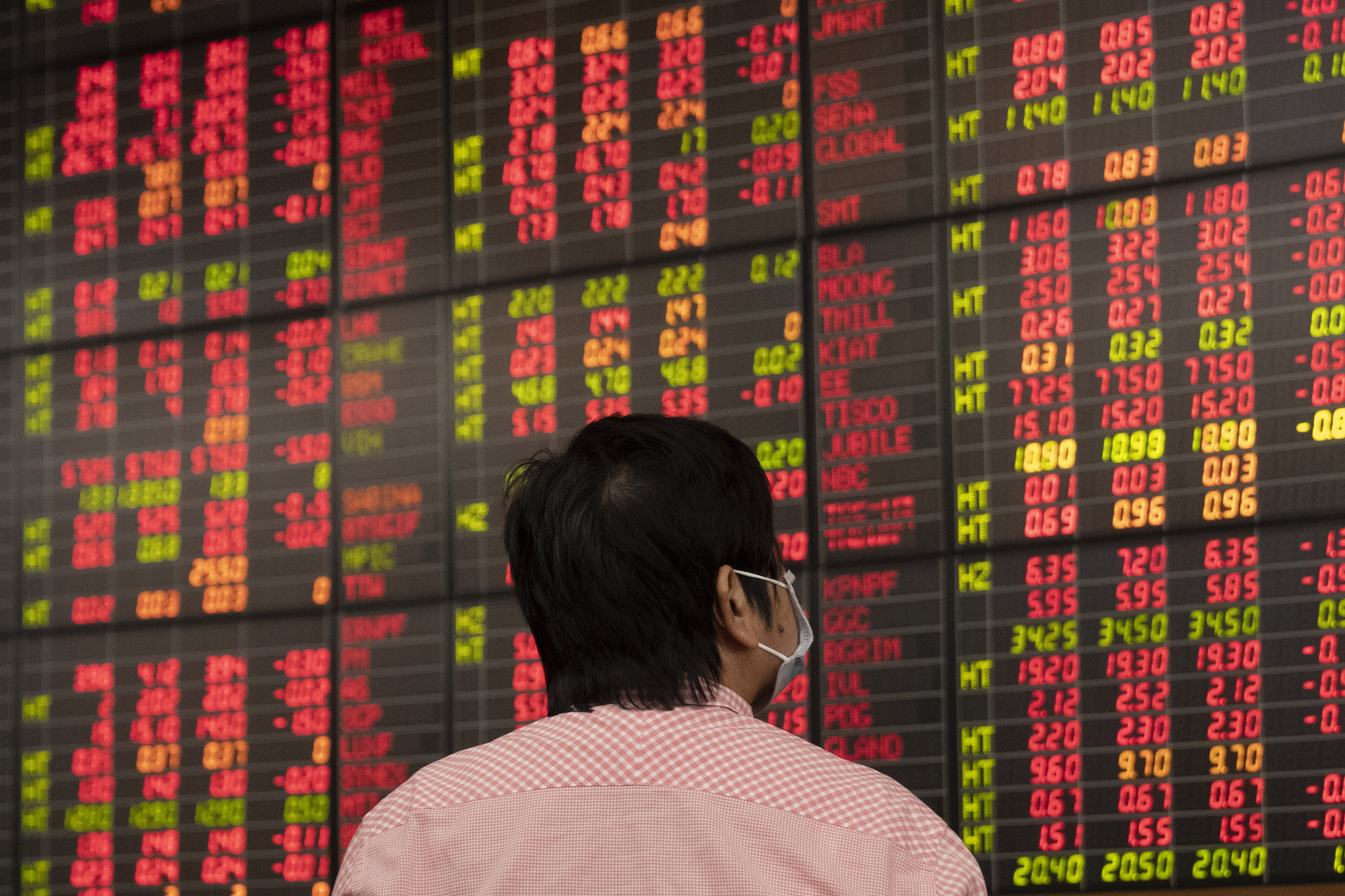 A Thai investor checks an electronic board showing stock prices at Asia Plus Securities, a private stock trading floor, in Bangkok, Thailand, Friday, March 13, 2020. (AP Photo/Sakchai Lalit)