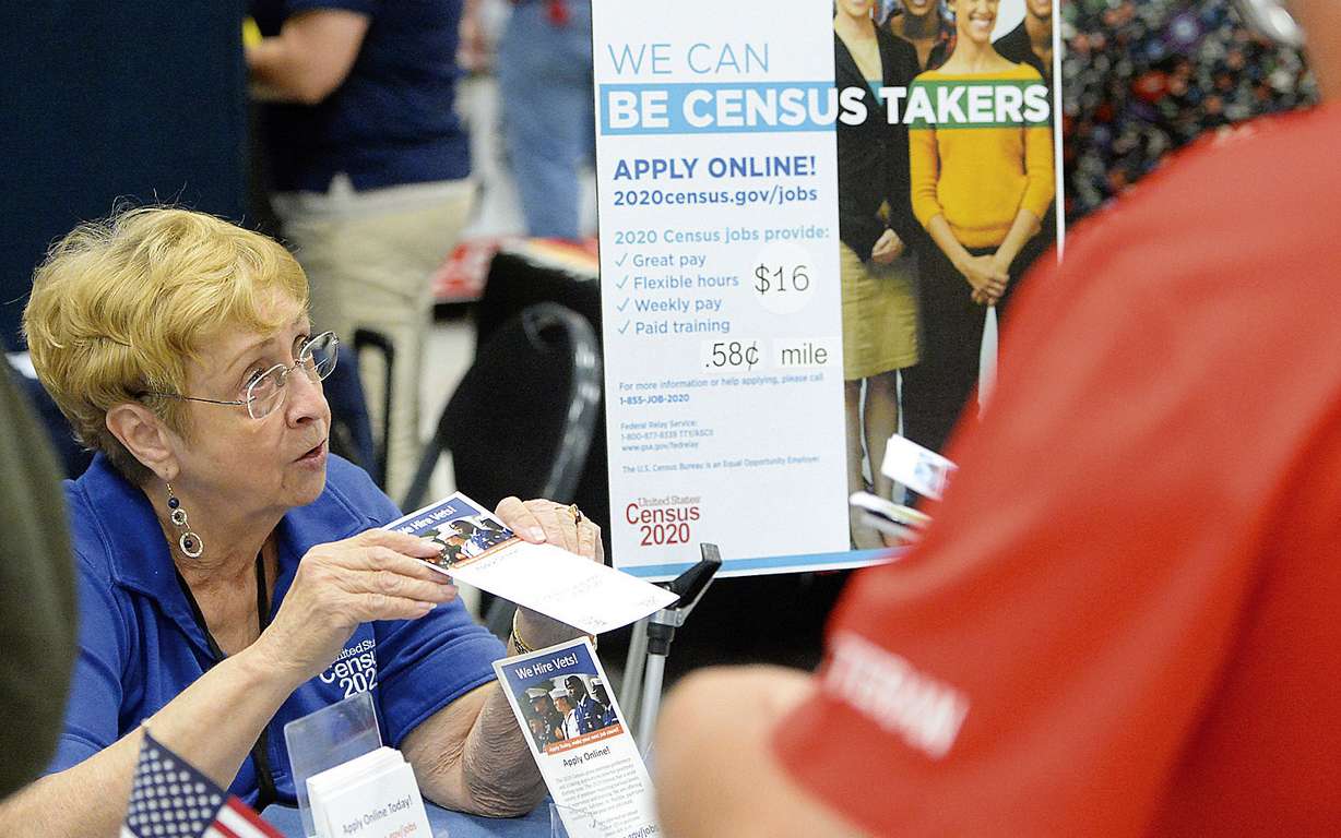 FILE - In this Oct. 2, 2019 file photo, Joyce Dalbey, left, with the U.S. Census Bureau, talks to attendees at the Yuma Community Job & Education Fair inside the Yuma Civic Center about possible job opportunities with the federal agency, in Yuma, Ariz. The U.S. Census Bureau said it has reached its goal of recruiting more than 2.6 million applicants for the once-a-decade head count that launched for most of America this week — but it has been a bumpy road getting there. (Randy Hoeft, The Yuma Sun via AP)