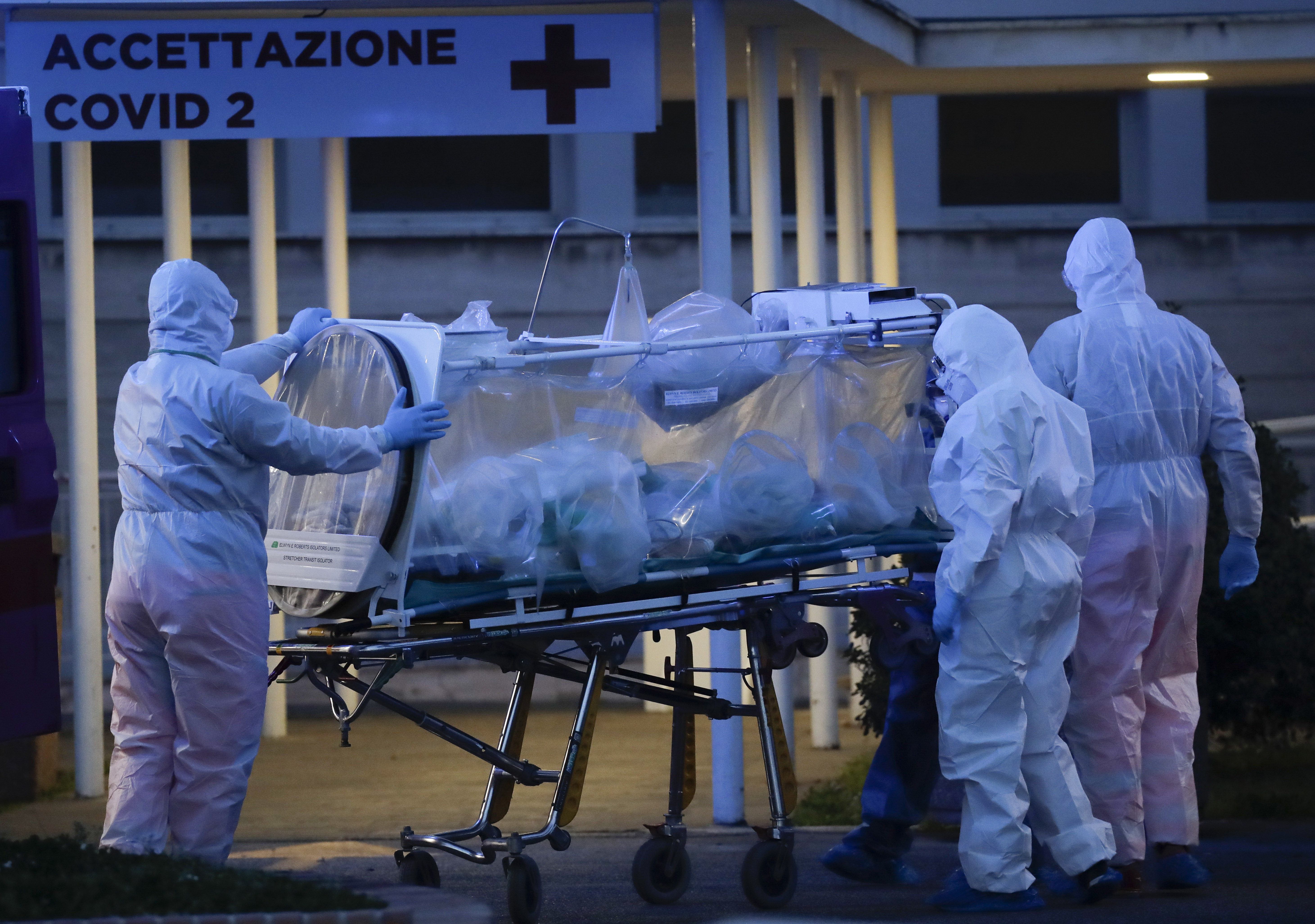 A patient in a biocontainment unit is carried on a stretcher at the Columbus Covid 2 Hospital in Rome, Monday, March 16, 2020. The new Columbus Covid 2 Hospital, an area fully dedicated to the COVID-19 cases at the Gemelli university polyclinic, opened today with 21 new ICU units and 32 new beds, in order to support the regional health authorities in trying to contain the pandemic. Sign at top in Italian reads "Admission COVID 19". (Alessandra Tarantino, AP Photo)