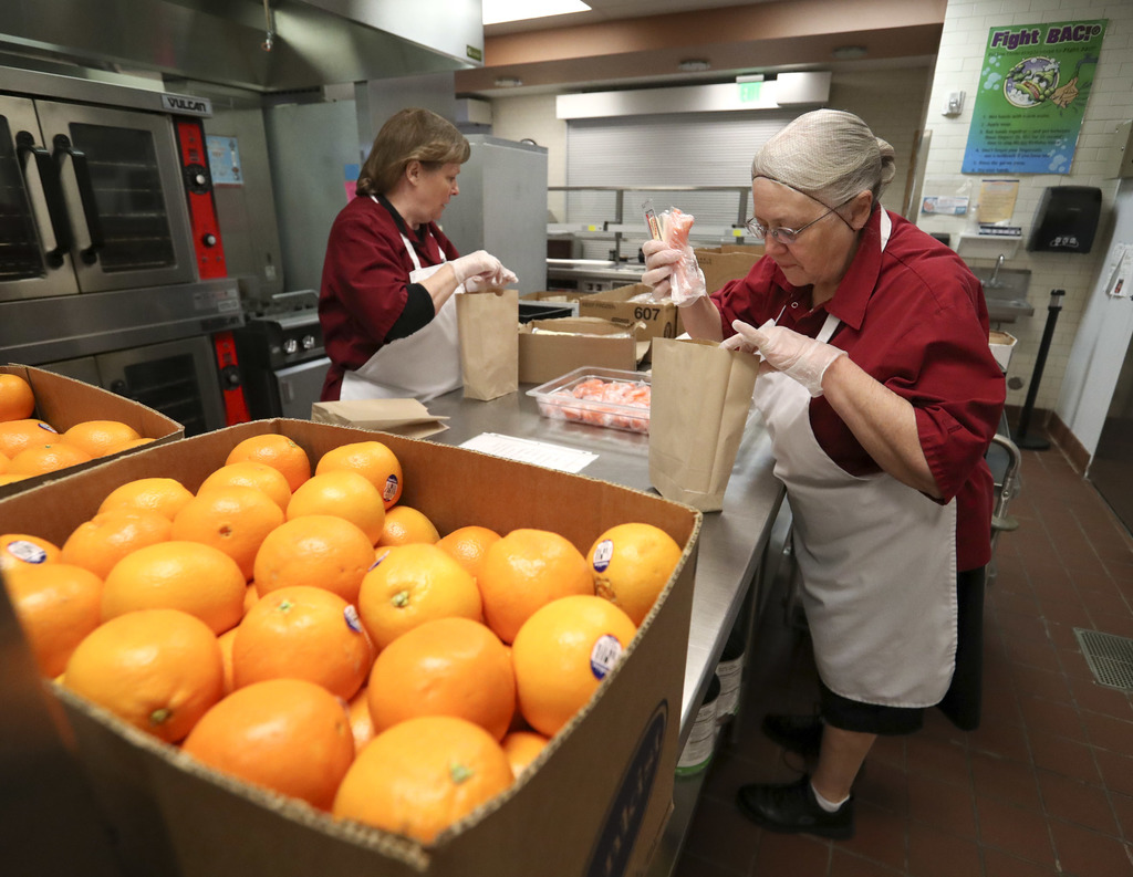 Sandra Anderson, left, manager of Midvale Elementary School's kitchen, and kitchen worker Arvilla Venneri prepare sack lunches at the school for students that can be picked up and taken home on Monday, March 16, 2020. On Friday Utah Gov. Gary Herbert and state health and education officials closed schools for two weeks to help stop the spread of COVID-19. (Photo: Steve Griffin, KSL)