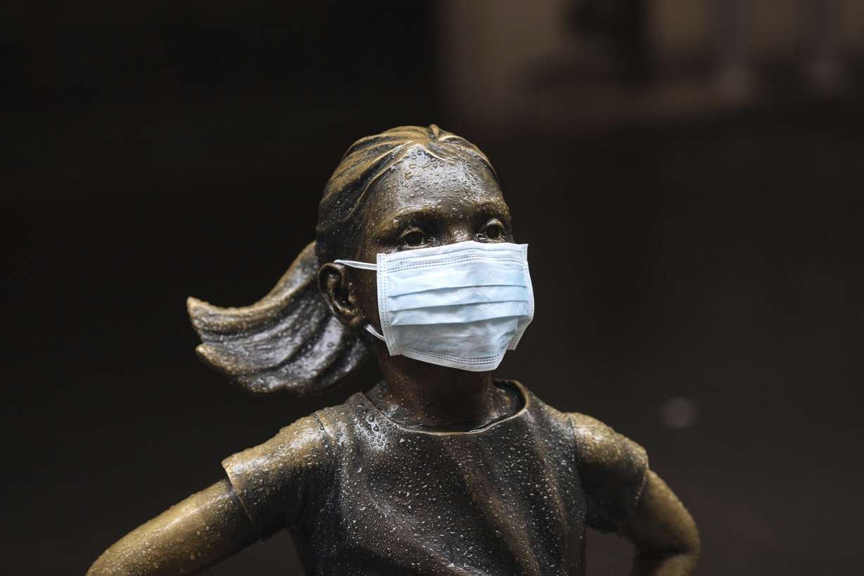 A surgical mask is placed on The "Fearless Girl" statue outside the New York Stock Exchange on Thursday, March 19, 2020, in New York. Stocks are swinging between gains and losses in early trading on Wall Street Thursday, but the moves are more subdued than the wild jabs that have dominated recent weeks. (Kevin Hagen, AP Photo)