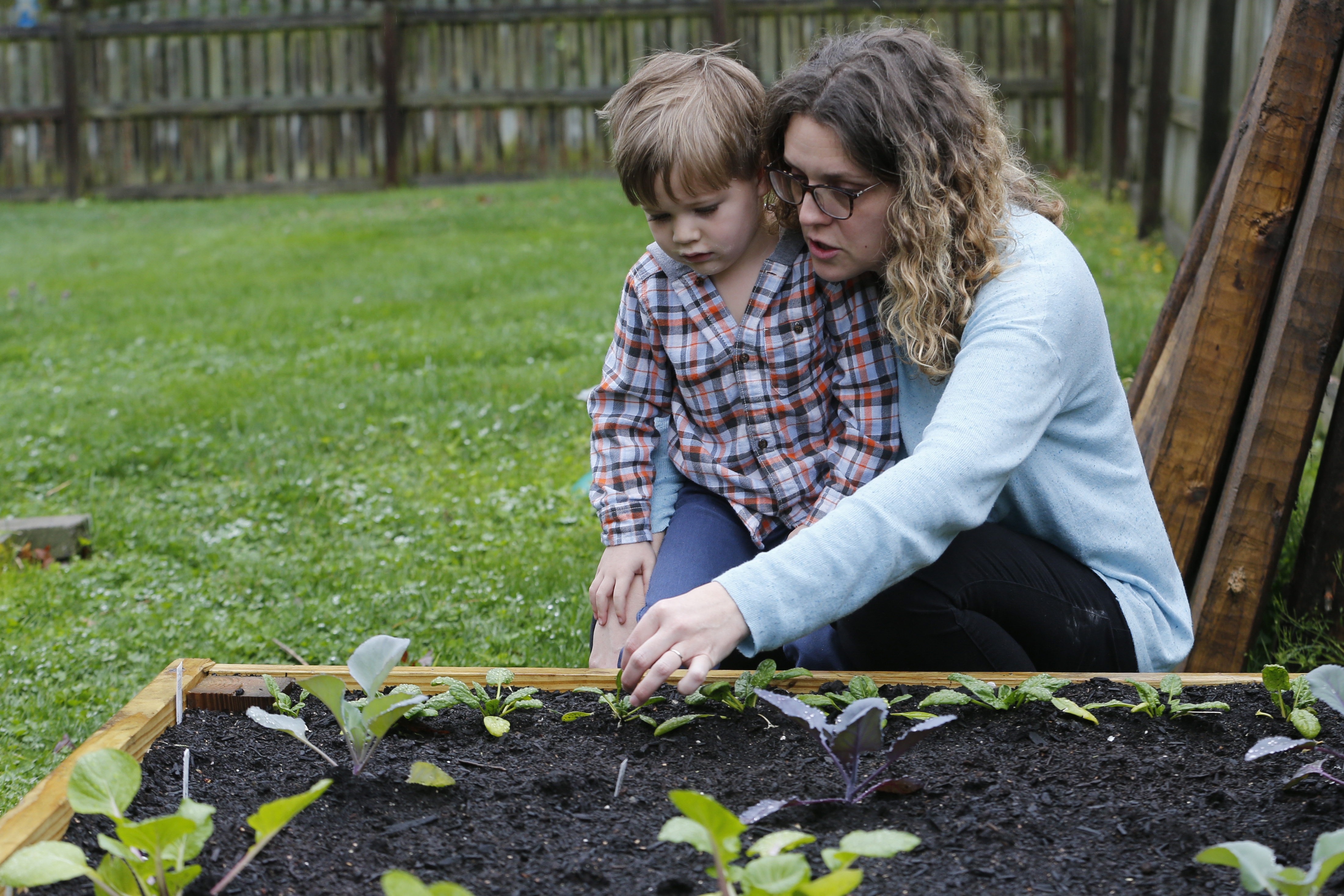 Stephanie Owens looks over the garden with her son, Cole, as they tend to it at their home Wednesday March 25, 2020, in Glen Allen, Va. Owens is a pharmacist who has had to continue to go to work, but has been able to spend more time with her kids because they are home from school. One of the activities that they have done is planting the garden. (AP Photo/Steve Helber)