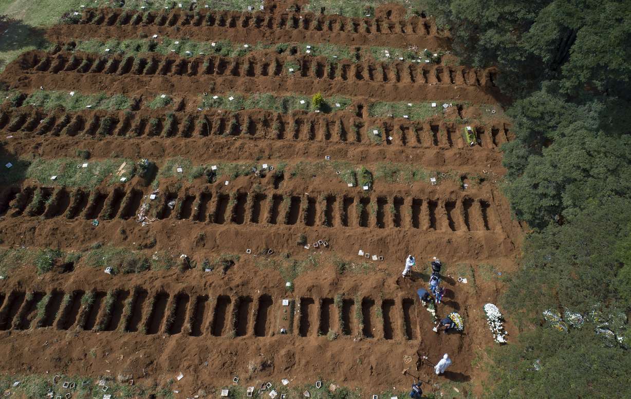 Cemetery workers in protective clothing bury a person at the Vila Formosa cemetery in Sao Paulo, Brazil, Wednesday, April 1, 2020. Vila Formosa cemetery, the largest in Latin America, has had a 30 percent increase in the number of burials amid spread of the new coronavirus, according to the cemetery's administration. (AP Photo/Andre Penner)