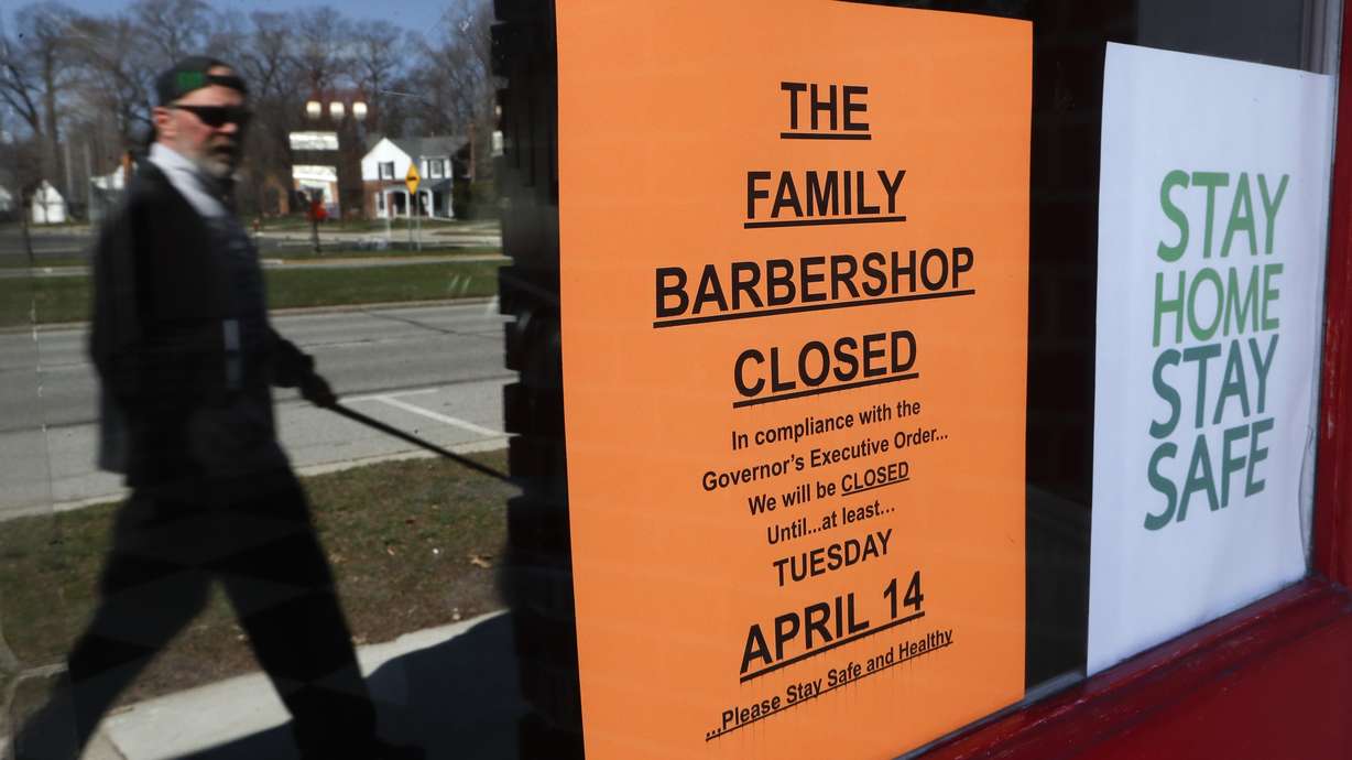 A pedestrian walks by The Family Barbershop, closed due to a Gov. Gretchen Whitmer executive order, in Grosse Pointe Woods, Mich., Thursday, April 2, 2020. (AP Photo/Paul Sancya)