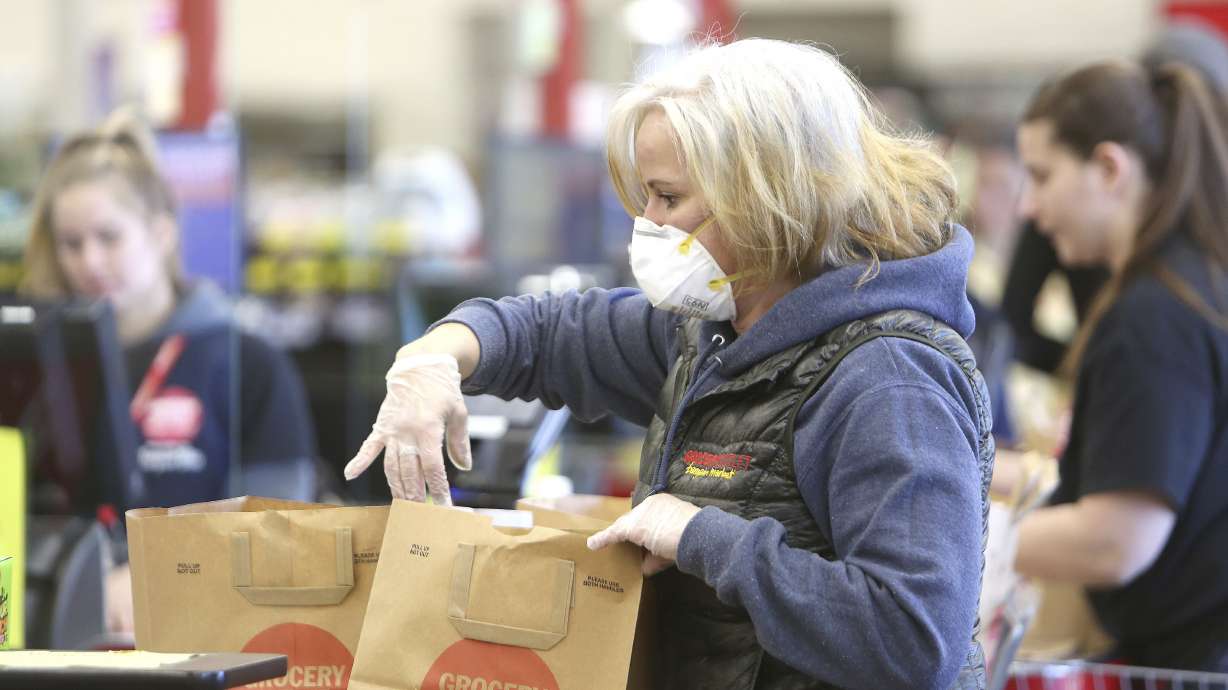 Grocery Outlet's Kasandra Berry, wears an N95 mask while helping to bag groceries last week in Grass Valley, Calif.