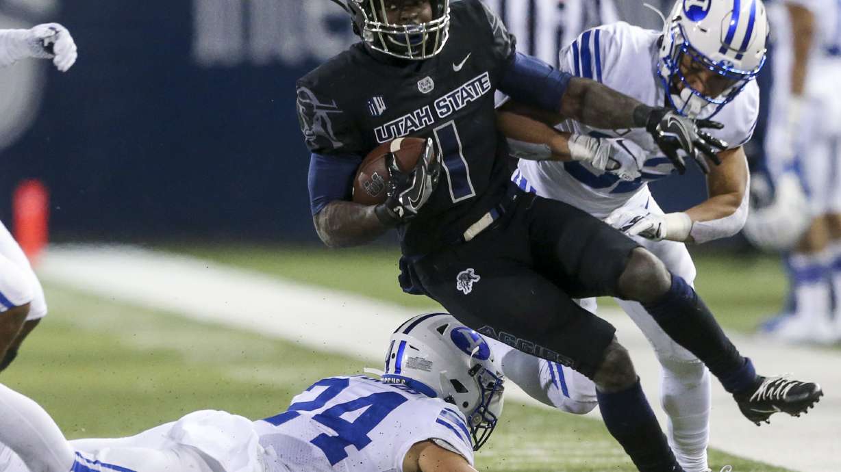 Utah State Aggies running back Gerold Bright (1) keeps the run alive, avoiding Brigham Young Cougars defensive back Chris Wilcox (32) and breaking defensive back Austin Kafentzis' (24) tackle during the second half of an NCAA football game at Maverik Stadium in Logan on Saturday, Nov. 2, 2019. The Brigham Young Cougars took back the wagon wheel in a dominant 42-14 victory over the Utah State Aggies.