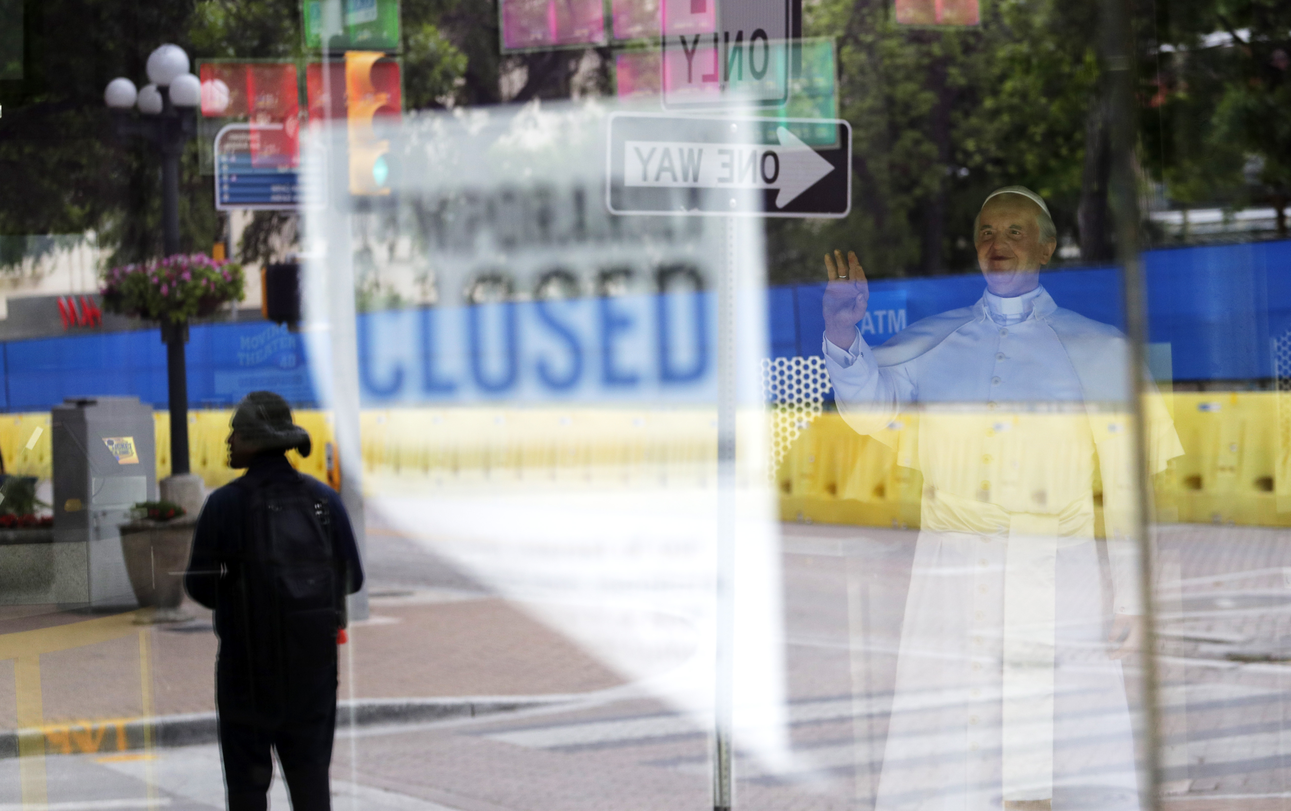 FILE - In this April 10, 2020, file photo, a pedestrian is reflected with a temporary closed sign in the window of a wax museum where a statue of Pope Francis is on display in San Antonio. For libertarians the very thought of massive government aid or the enforced closings of businesses is usually indefensible. But those beliefs can change in a time of crisis, like now. The spread of the coronavirus has renewed a long-running debate among libertarians over such core beliefs as private enterprise and individual autonomy. (AP Photo/Eric Gay, File)