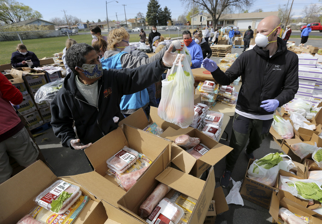 Jose Magallanes hands a bag of food to Chris Tibbitts as they prepare to hand out food from the Utah Food Bank in the parking lot of a chapel belonging to The Church of Jesus Christ of Latter-day Saints in Taylorsville on Monday, April 13, 2020. The Utah Food Bank estimates they provided food to around 400 families at this location. (Photo: Kristin Murphy, KSL)