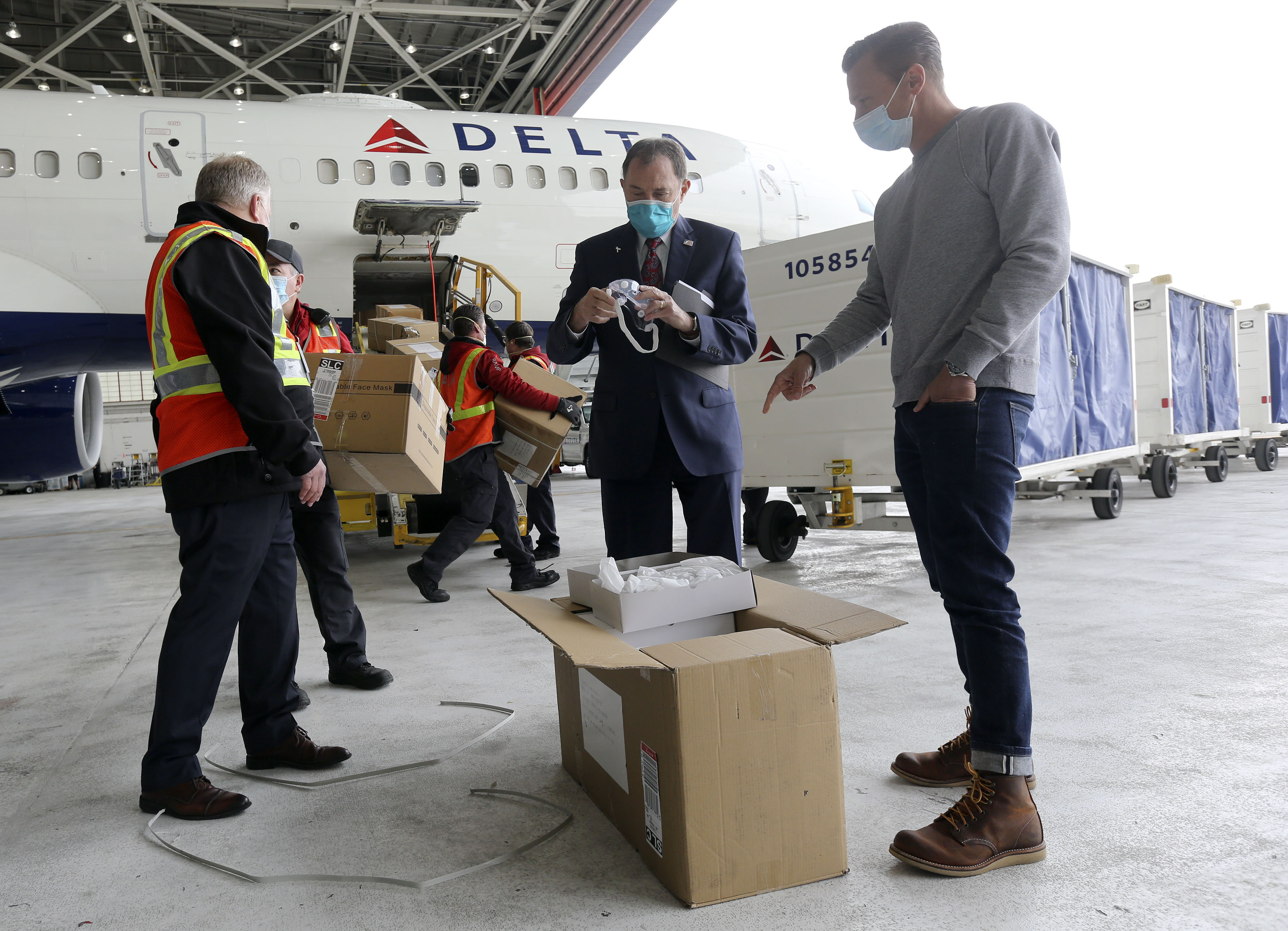 Gov. Gary Herbert, center, and Taylor Shupe, CEO of Future Stitch, look at eye protection that just arrived, along with KN95 masks, at the Salt Lake City International Airport on Wednesday, April 15, 2020. (Kristin Murphy, KSL)
