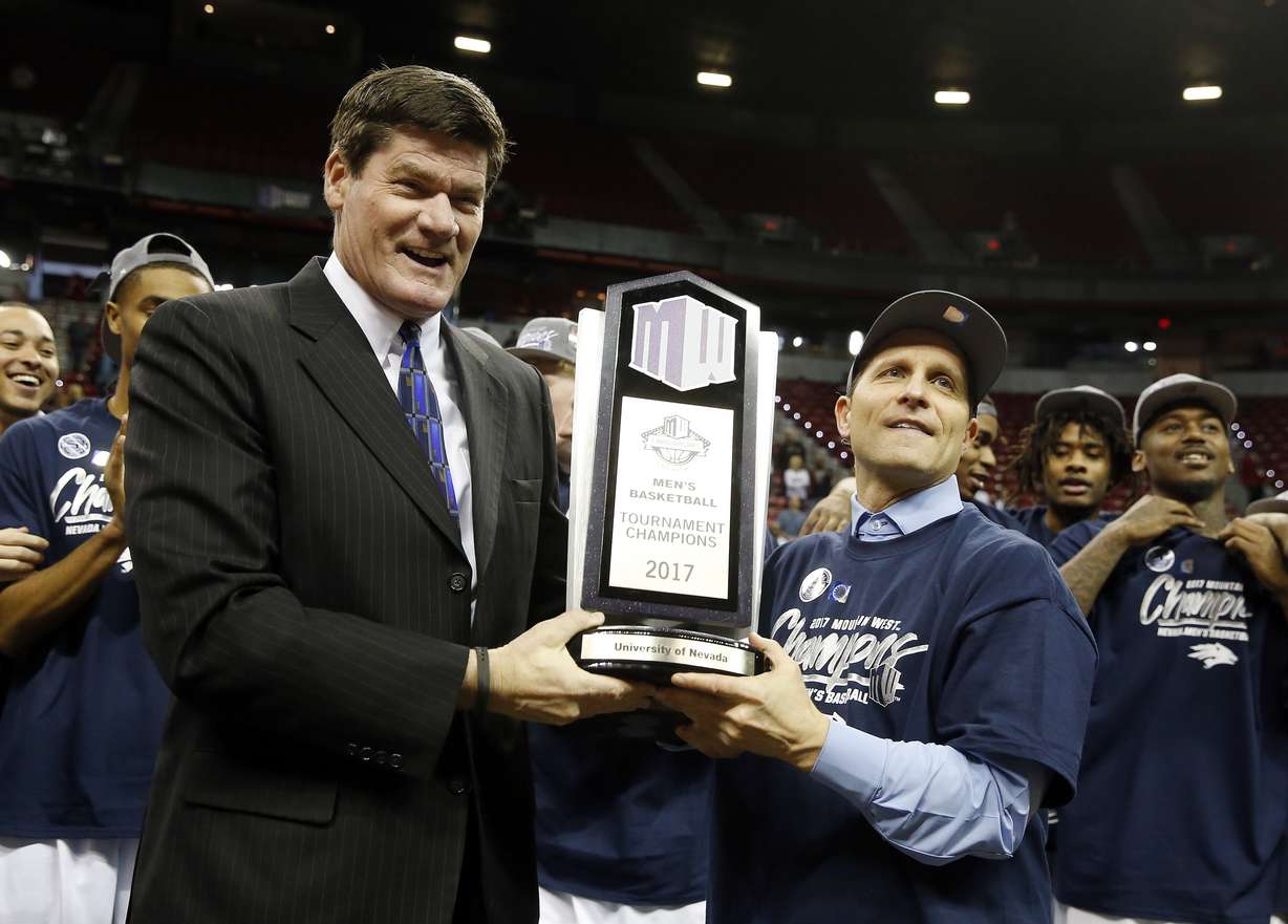 Mountain West Conference Commissioner Craig Thompson, left, presents Nevada coach Eric Musselman with the trophy after Nevada defeated Colorado State 79-71 in an NCAA college basketball game for the conference title, Saturday, March 11, 2017, in Las Vegas.