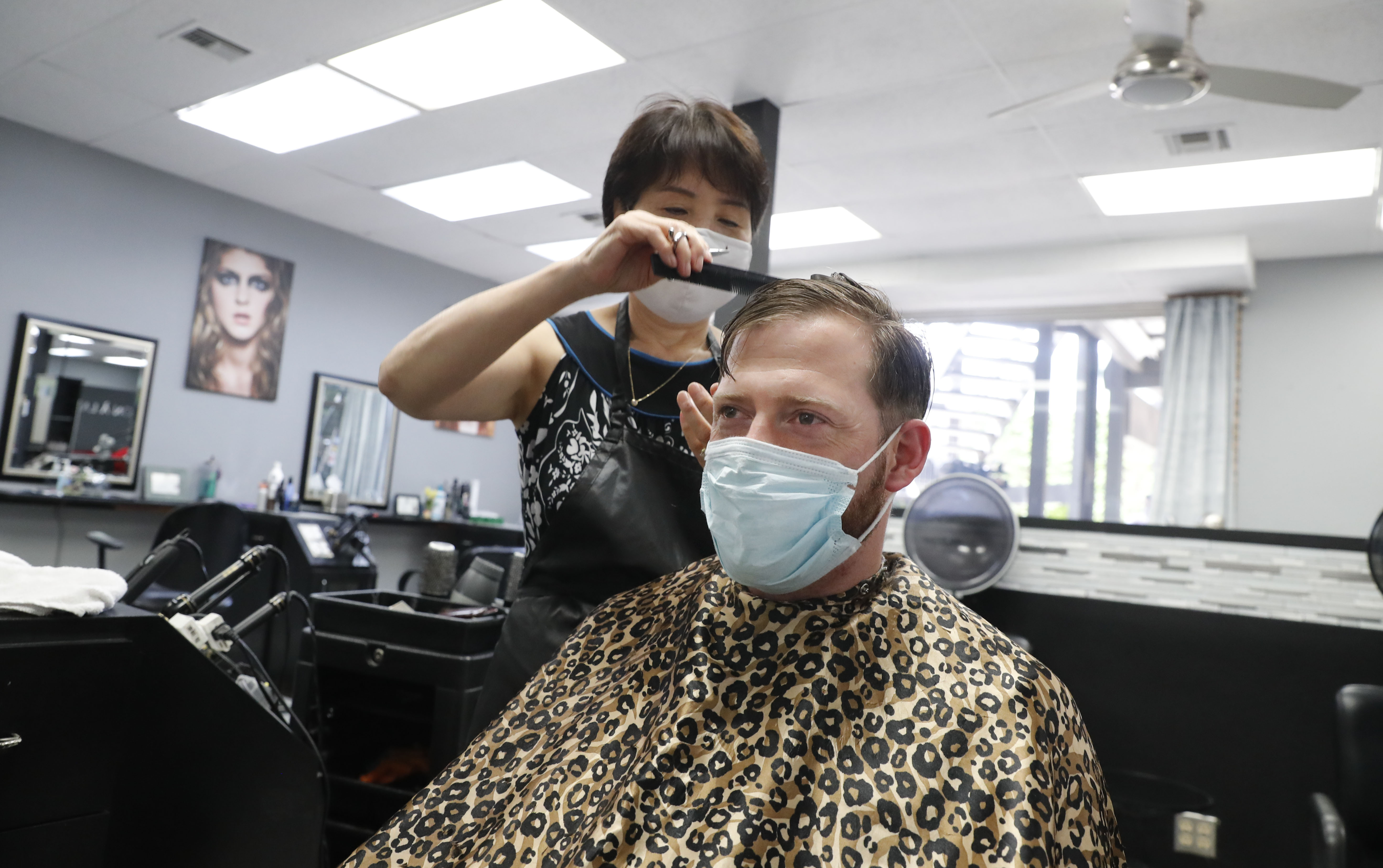 Amid concerns of the spread of COVID-19, Joe Farley, front, wears a mask as he gets a haircut from Kim at the just reopened Salon A la Mode in Dallas, Friday, April 24, 2020. (AP Photo/LM Otero)