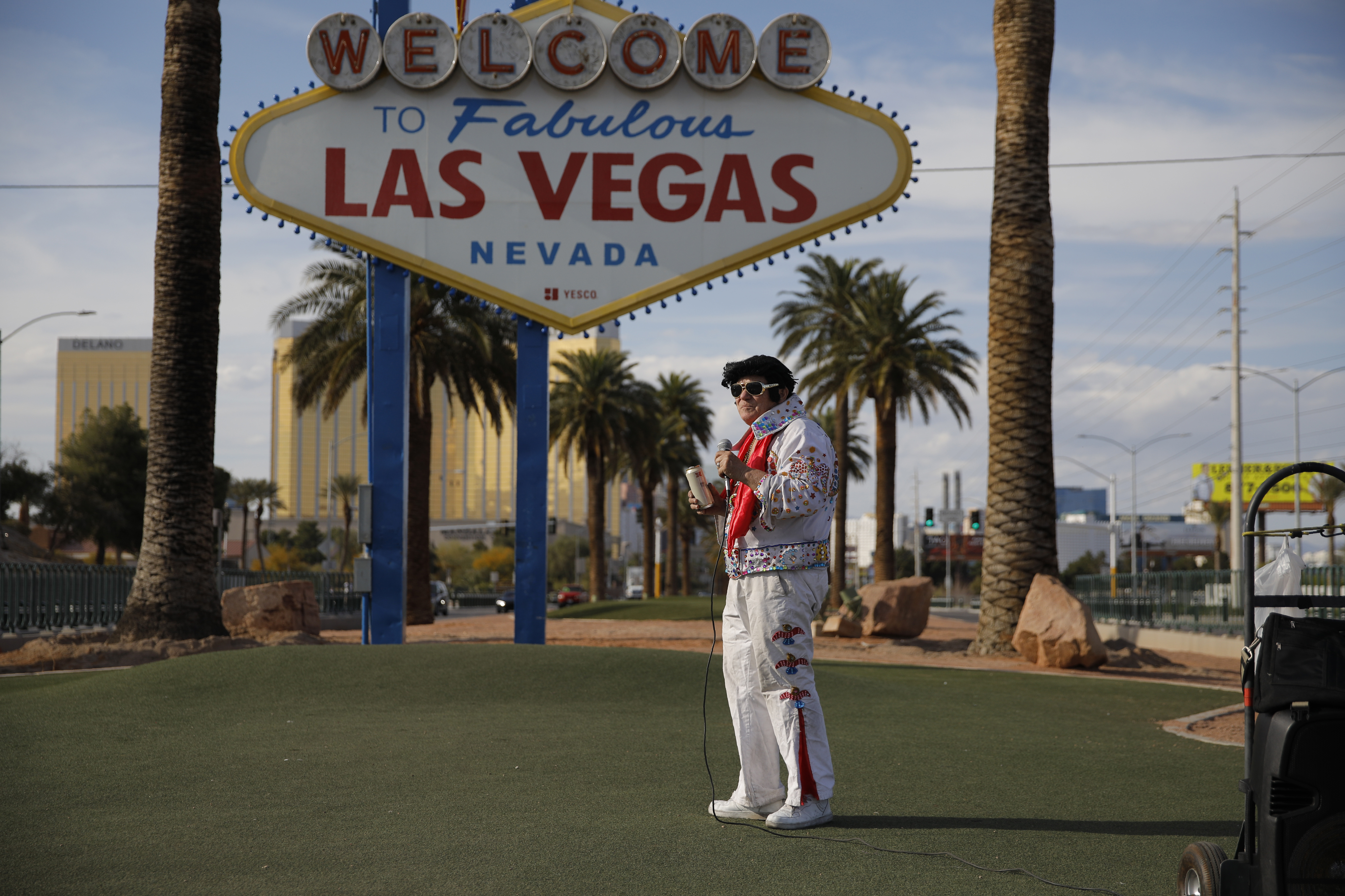 In this April 16, 2020, photo, Chris Morehouse drinks a beer while performing as Elvis at the "Welcome to Fabulous Las Vegas Nevada" sign along the Strip in Las Vegas. "I'm just singing for the sign," said Morehouse who was at times performing save the few locals who occasionally took advantage of the eerie silence to take photos at the sign. (Photo: John Locher, AP Photo)