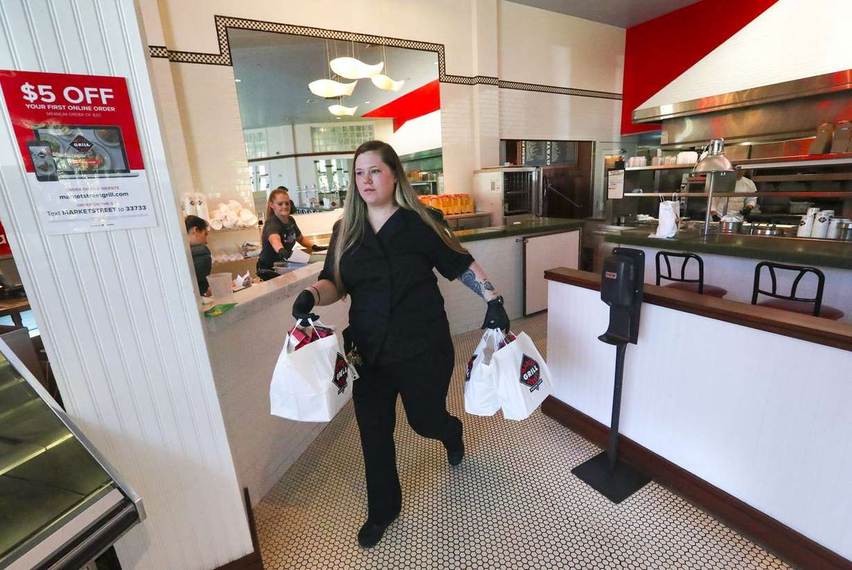 Tashina Hathaway, manager of the Market Street Grill location in Cottonwood Heights, delivers curbside pickup orders to a customers on Tuesday, April 28, 2020. (Photo: Steve Griffin, KSL)