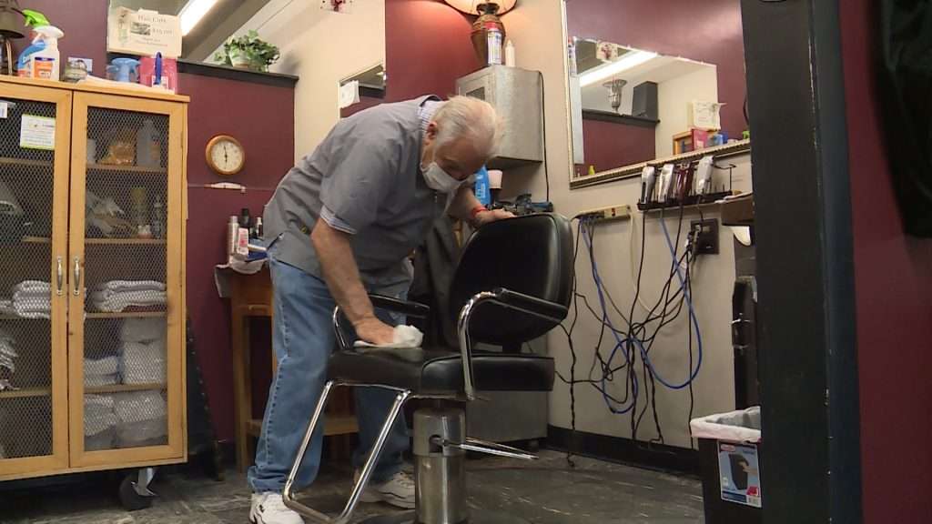 Lenny Pagano wipes down a chair between customers Tuesday, April 28, 2020. (Photo: KSL TV)