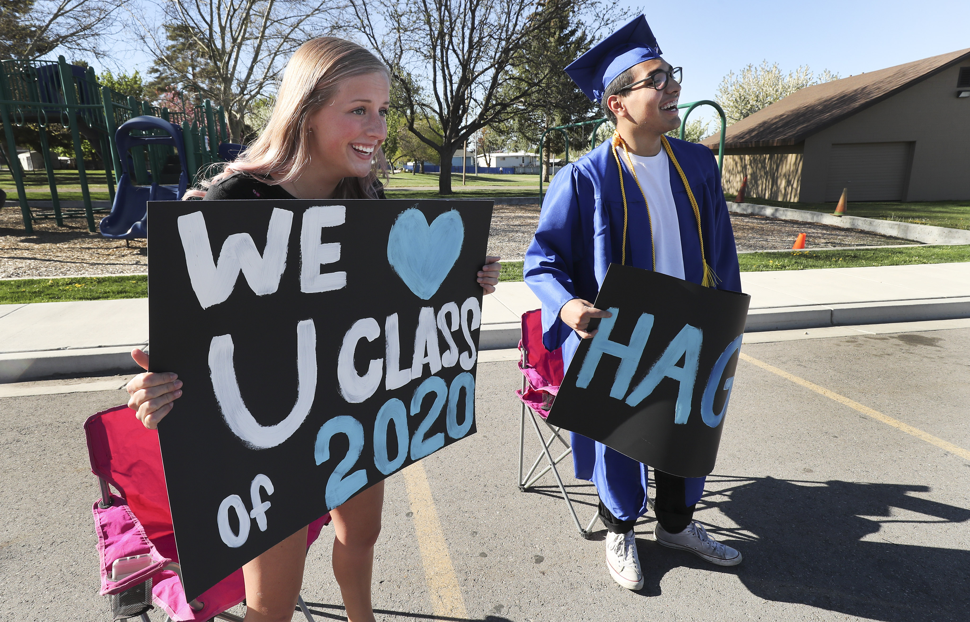 Emily Trewartha, Pleasant Grove High School student body vice president, and Francisco Calderon, student body president holds signs as seniors pick up caps, gowns, honor cords and yard signs at the school in Pleasant Grove on Wednesday, April 29, 2020. At the end of May, the school will also provide a “graduation walk” experience at the school over four days. Graduates and their immediate family will schedule a time to enter the auditorium, where “Pomp and Circumstance” will be playing and students’ names will be read over the school’s sound system. (Photo: Jeffrey D. Allred, KSL)