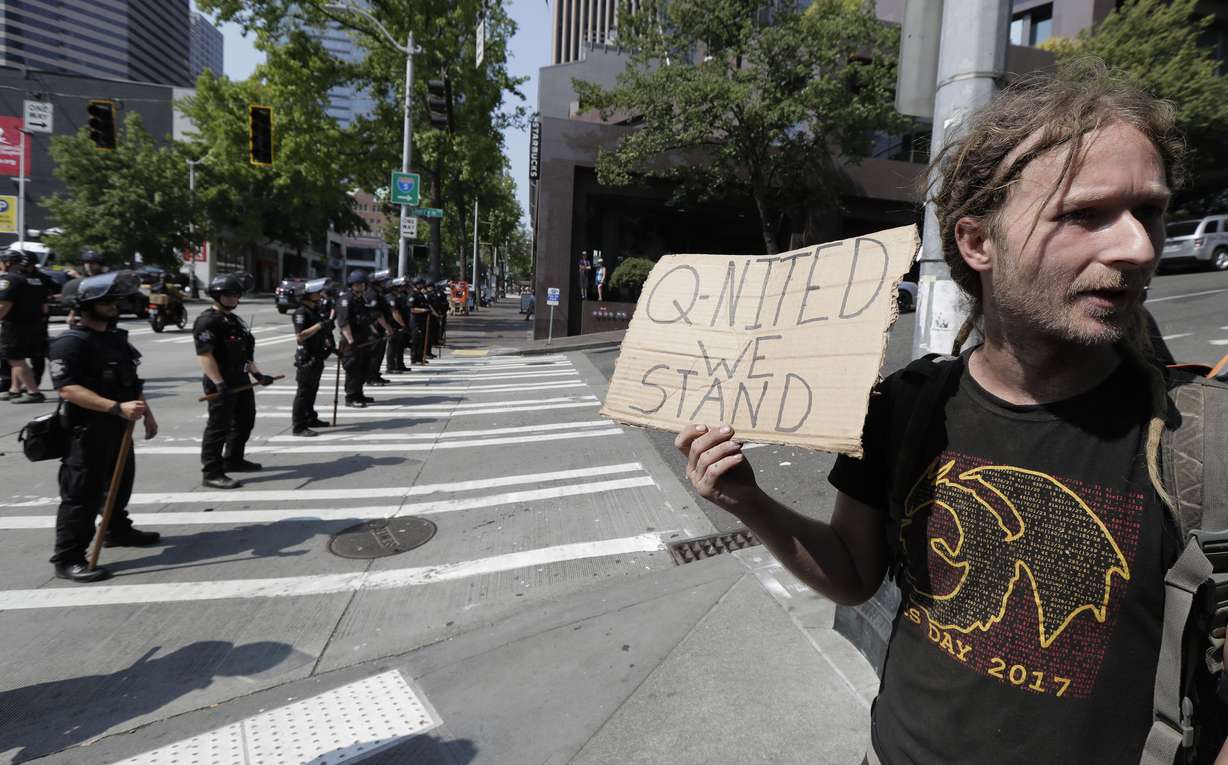 In this Aug. 18, 2018 file photo man holds a sign that reads "Q-Nited We Stand" during a rally held by members of Patriot Prayer and other groups supporting gun rights near City Hall in Seattle.