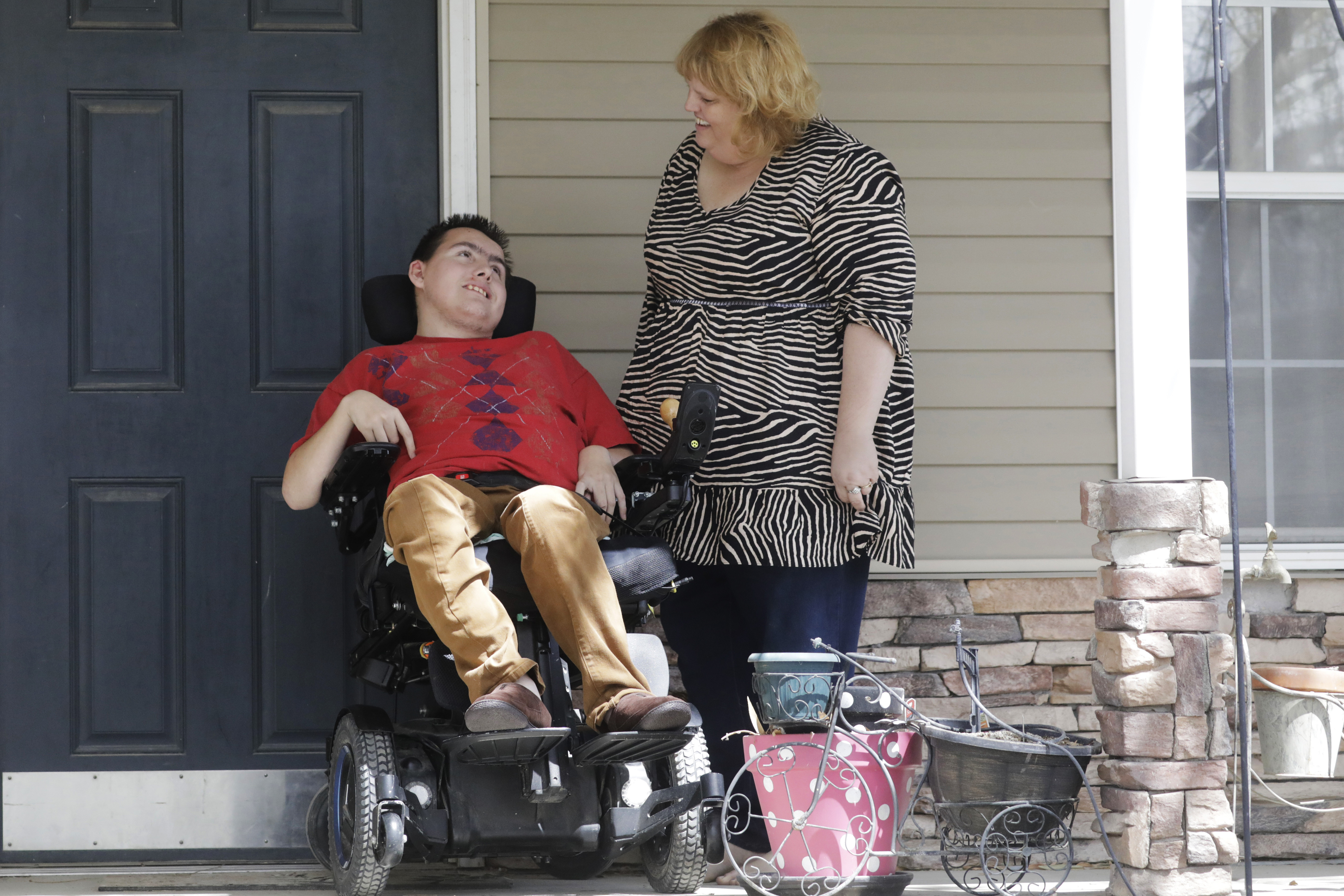 In this April 14, 2020, photo, Jodi Hansen talks with her son Jacob Hansen at their home, in Eagle Mountain, Utah. Even before the new coronavirus hit, cystic fibrosis meant a cold could put Jacob Hansen in the hospital for weeks. He relies on hand sanitizer and disinfecting wipes to keep germs at bay because has cerebral palsy and uses a wheelchair, but these days shelves are often bare. For millions of disabled people and their families, the coronavirus crisis has piled on new difficulties and ramped up those that already existed. (AP Photo/Rick Bowmer)