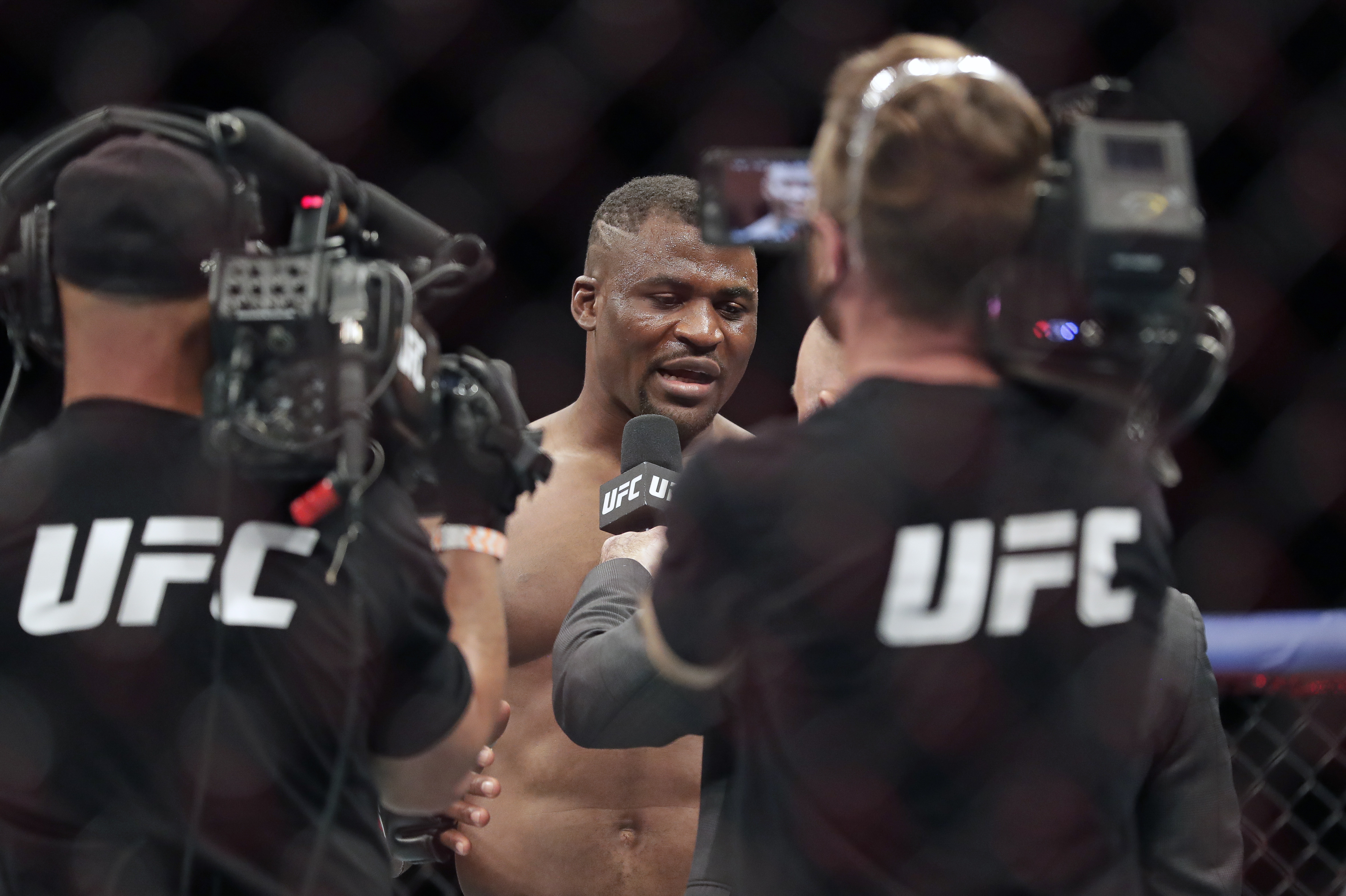 Francis Ngannou, center, is interviewed after winning a UFC 249 mixed martial arts bout against Jairzinho Rozenstruik, Saturday, May 9, 2020, in Jacksonville, Fla. (AP Photo/John Raoux)