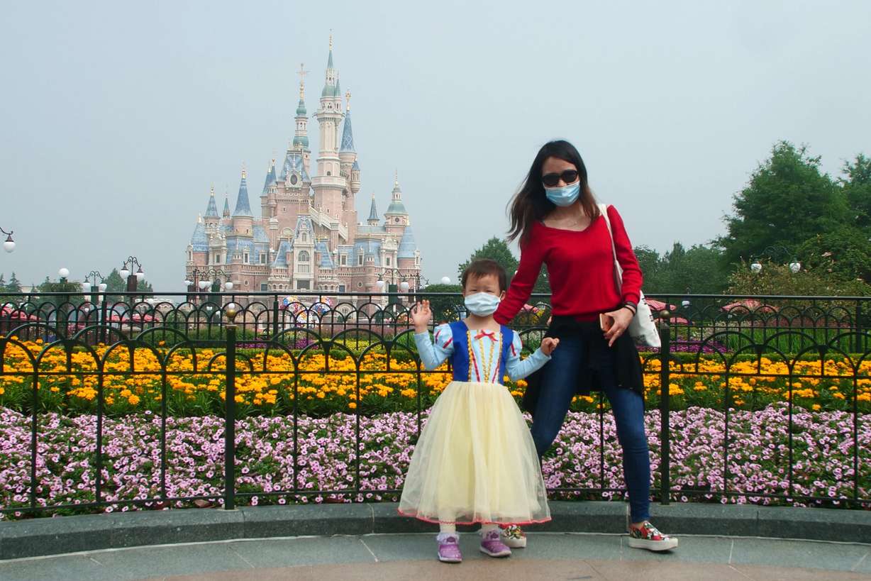 A young visitor, wearing face masks, waves at the Disneyland theme park in Shanghai as it reopened after the coronavirus closure, Monday, May 11, 2020. (Photo: Sam McNeil, AP Photo)