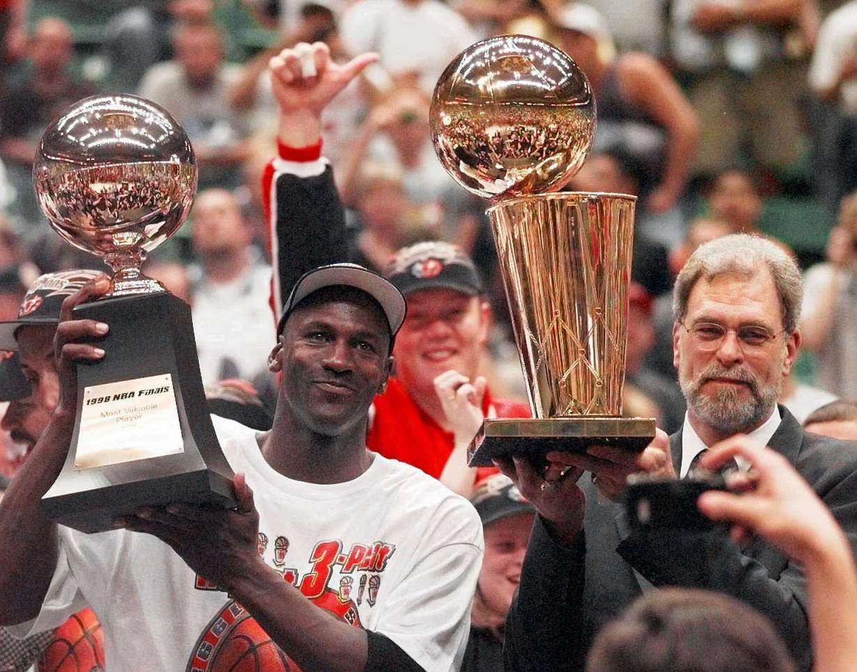 Chicago Bulls' Michael Jordan, left, holds the Most Valuable Player trophy as coach Phil Jackson holds the NBA championship trophy after the Bulls defeated the Utah Jazz 87-86 in Game 6 of the NBA Finals in Salt Lake City, in this June 14, 1998 photo. (Photo: Jack Smith, AP)